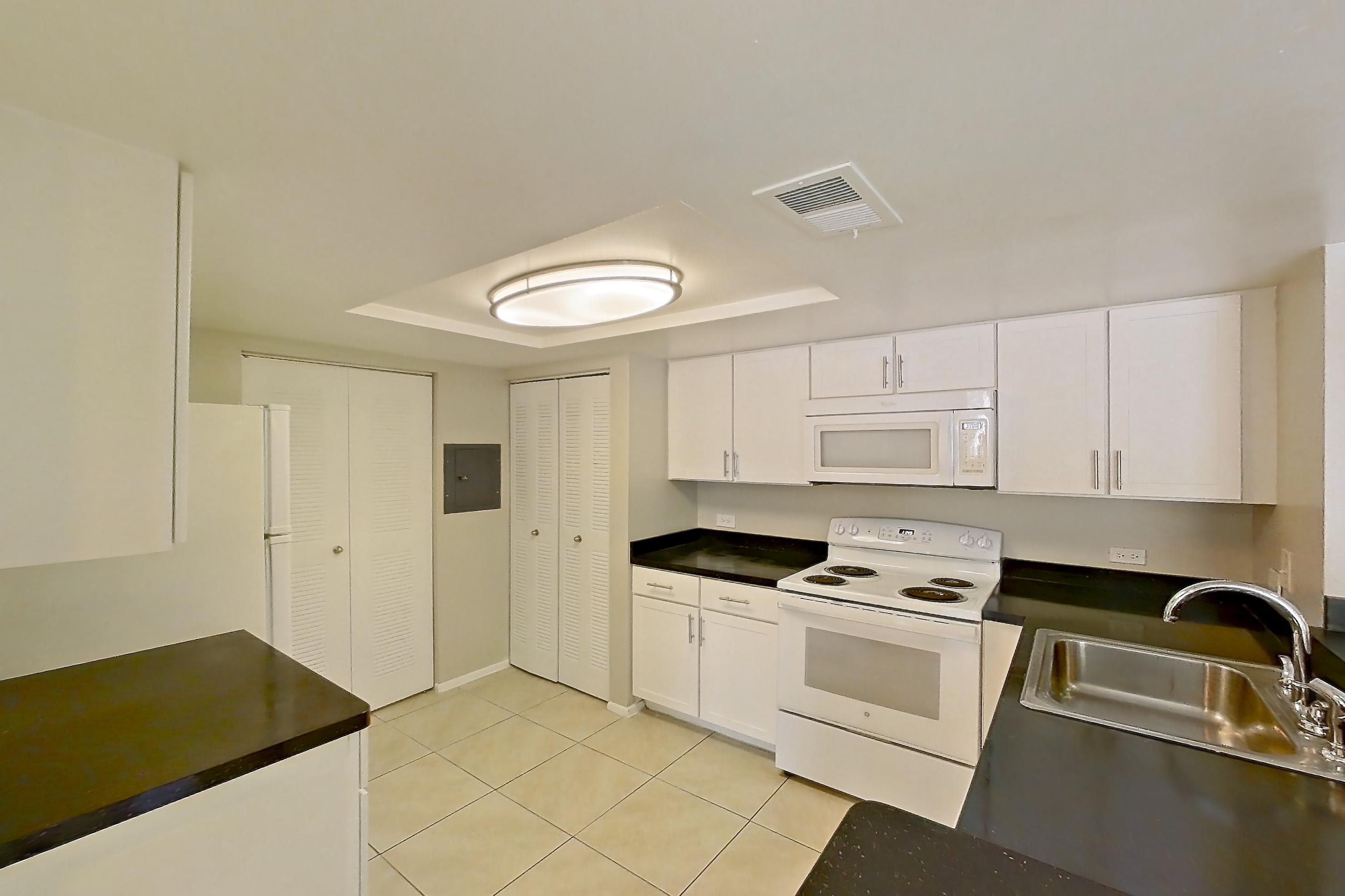 Kitchen entryway with dark countertops, electric range, light countertops, light tile flooring, oven/range, and white appliances, Apartment 01-11838 at Sabal Pointe