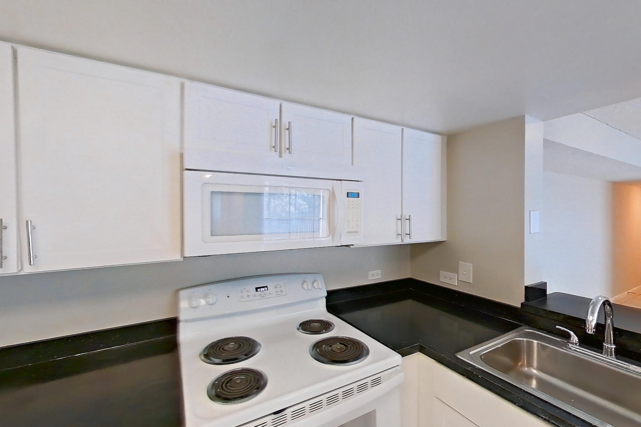 Kitchen with dark countertops, dishwasher, electric range, light tile flooring, microwave, oven/range, and white appliances, Apartment 01-11838 at Sabal Pointe