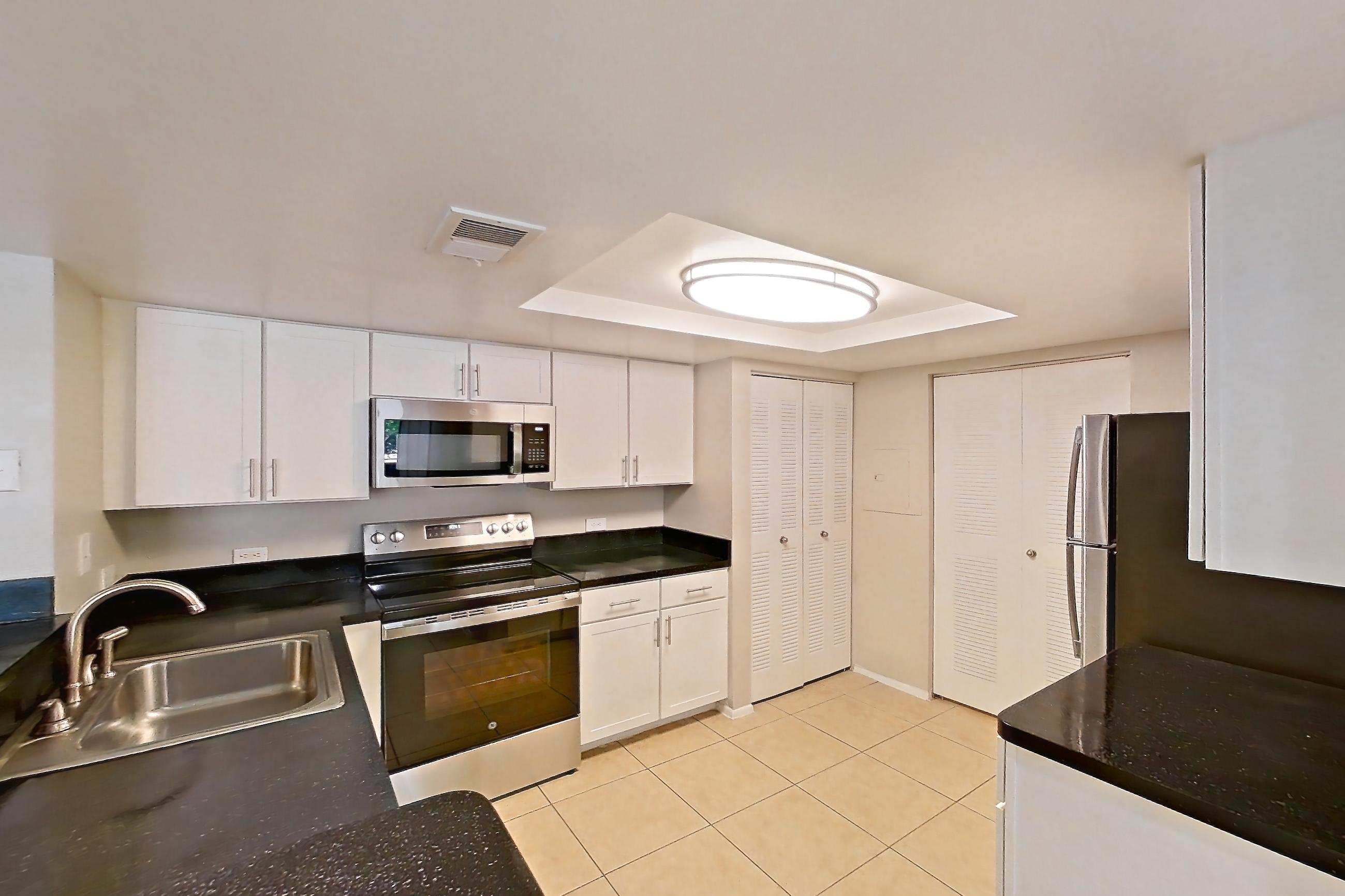 Kitchen entryway with dark countertops, electric range, light countertops, light tile flooring, oven/range, refrigerator, and stainless steel appliances, Apartment 03-11932 at Sabal Pointe
