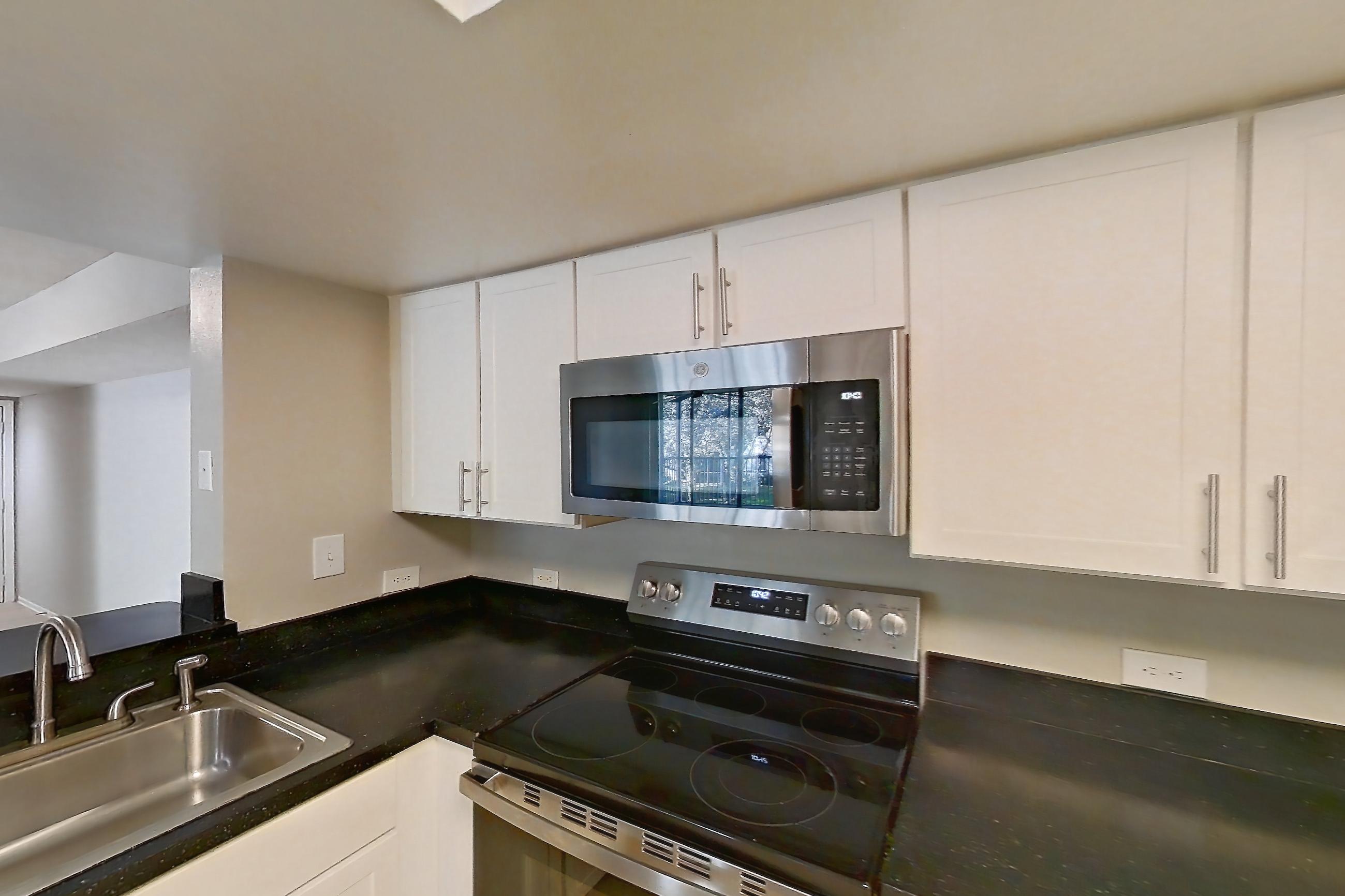 Kitchen with dark countertops, dishwasher, electric range, light tile flooring, microwave, oven/range, refrigerator, and stainless steel appliances, Apartment 03-11932 at Sabal Pointe