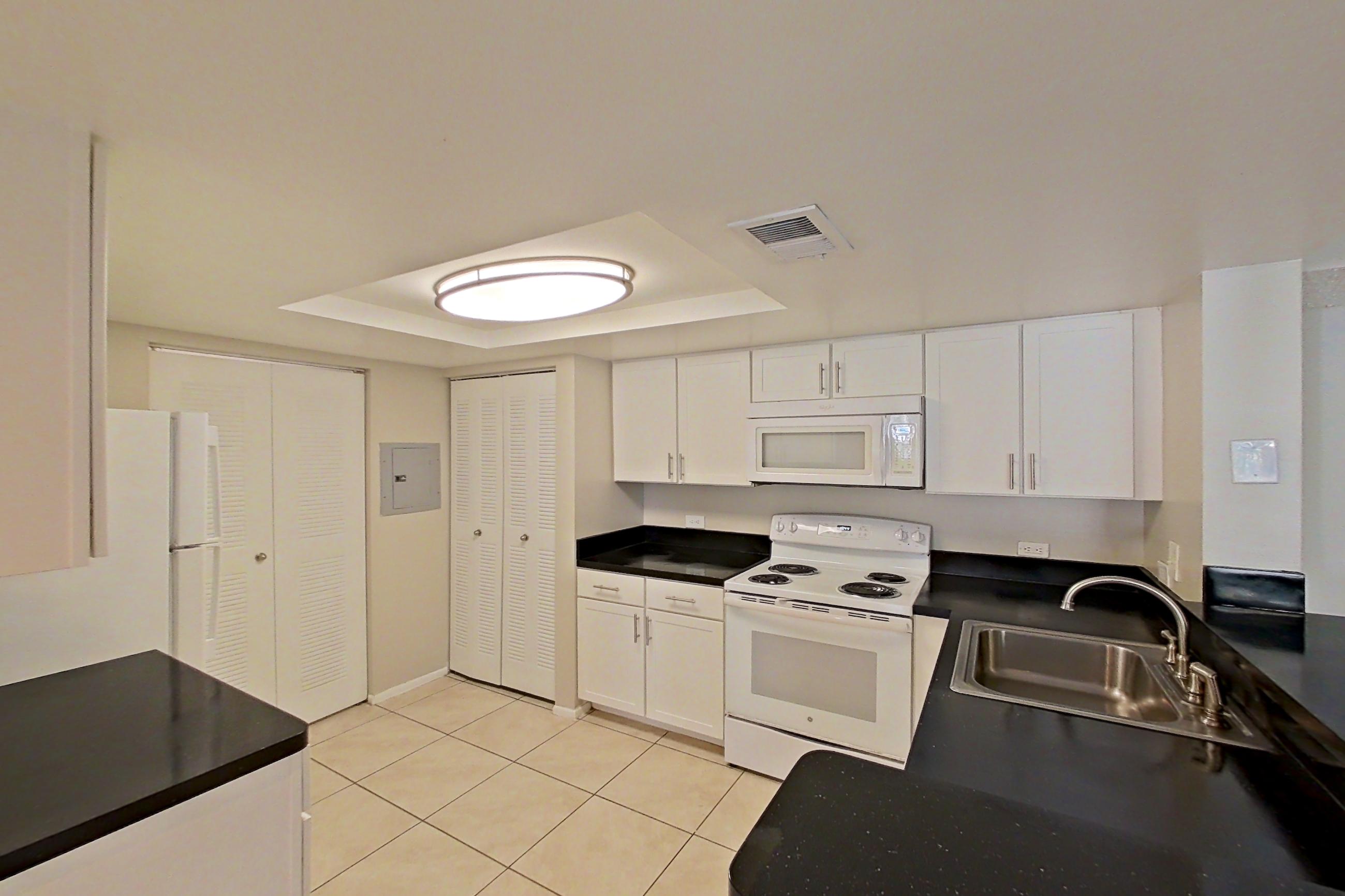 Kitchen entryway with dark countertops, electric range, light countertops, light tile flooring, oven/range, and white appliances, Apartment 03-11934 at Sabal Pointe