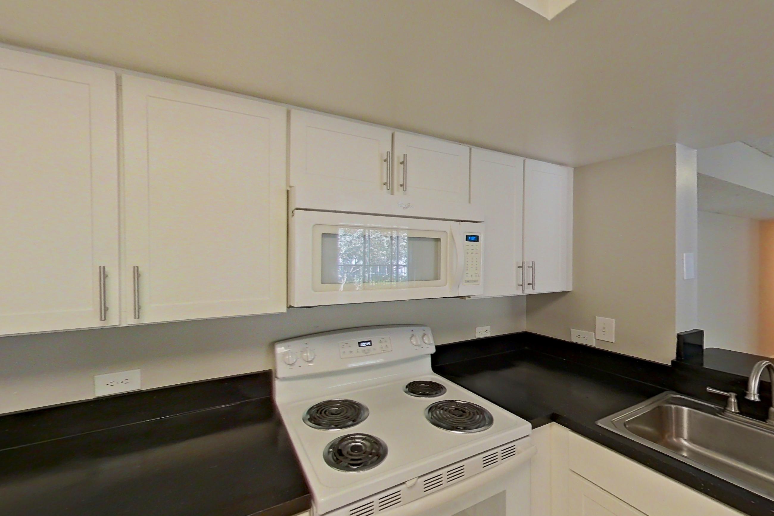Kitchen with dark countertops, dishwasher, electric range, light tile flooring, microwave, oven/range, and white appliances, Apartment 03-11934 at Sabal Pointe