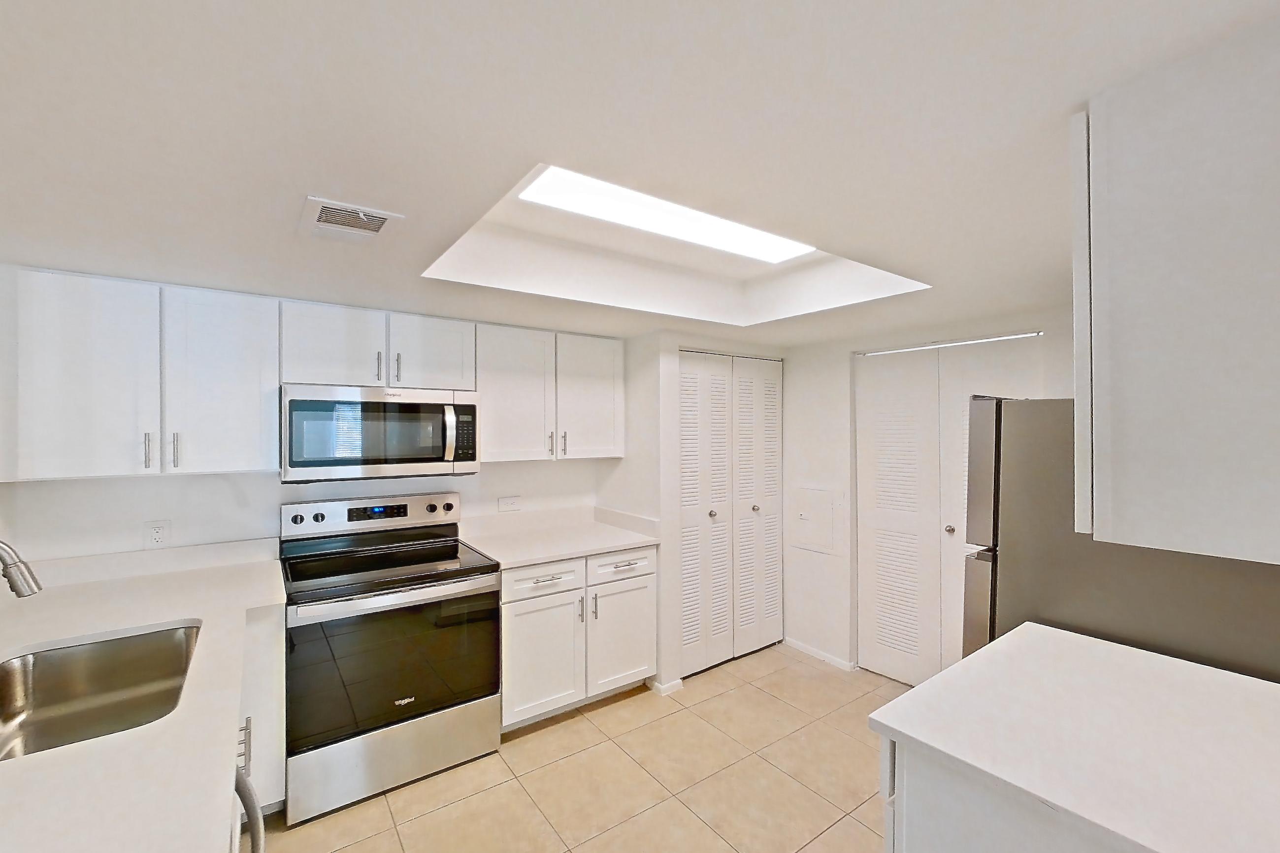 Kitchen entryway with electric range, light countertops, light tile flooring, microwave, oven/range, and stainless steel appliances, Apartment 06-12074 at Sabal Pointe