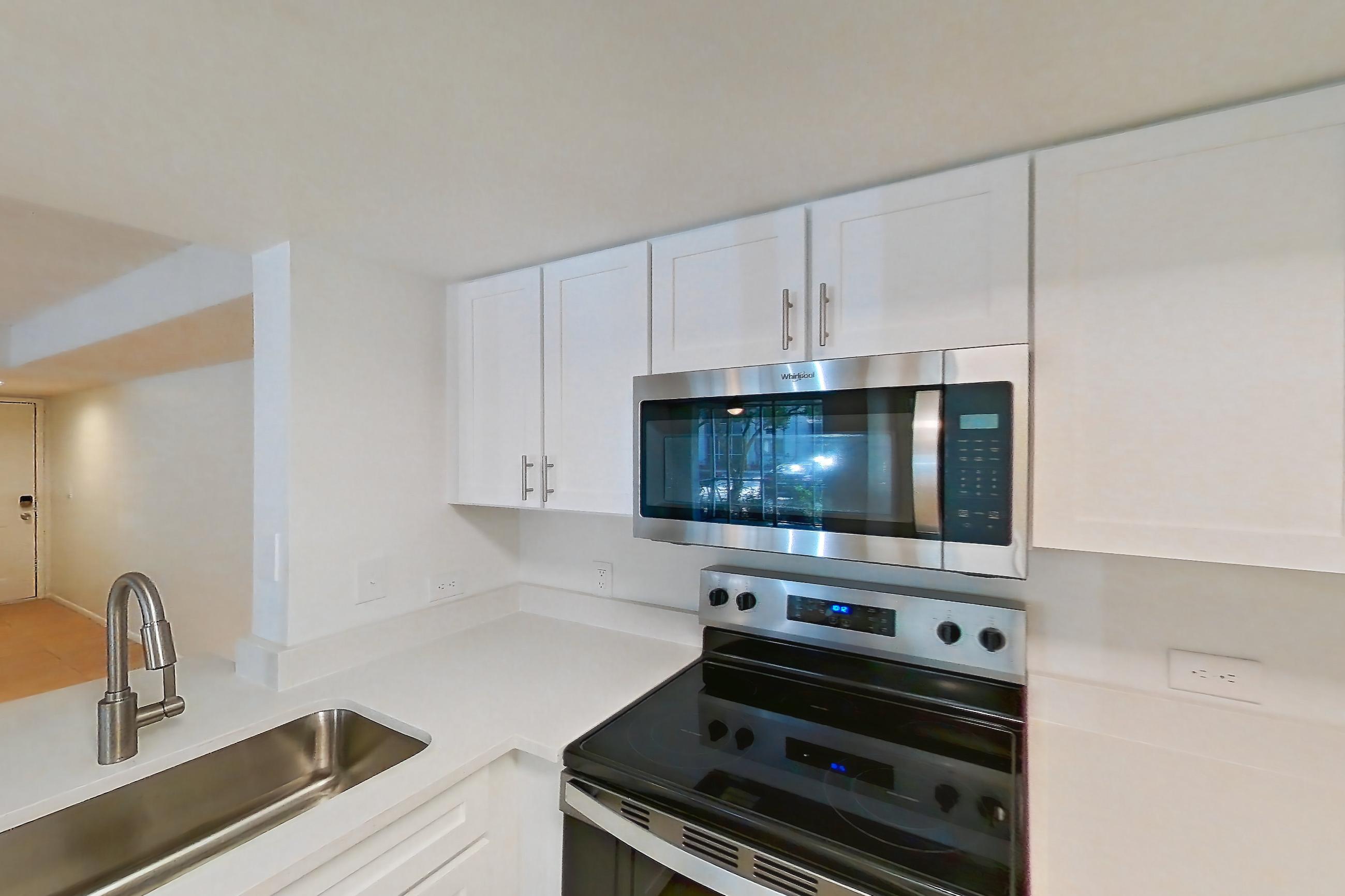Kitchen with dishwasher, electric range, light countertops, light stone countertops, light tile flooring, microwave, oven/range, refrigerator, and stainless steel appliances, Apartment 06-12074 at Sabal Pointe