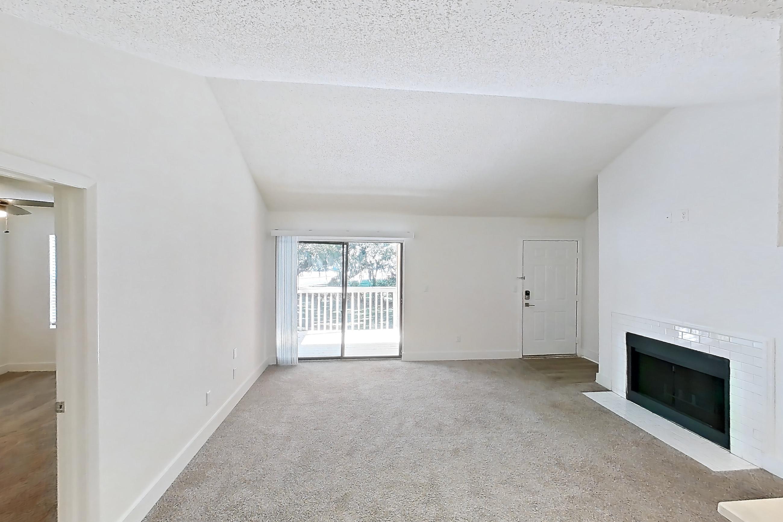 Dining room with electric range, fireplace, light carpet, light stone countertops, oven/range, refrigerator, and stainless steel appliances, Apartment 20-207 at St. James Crossing