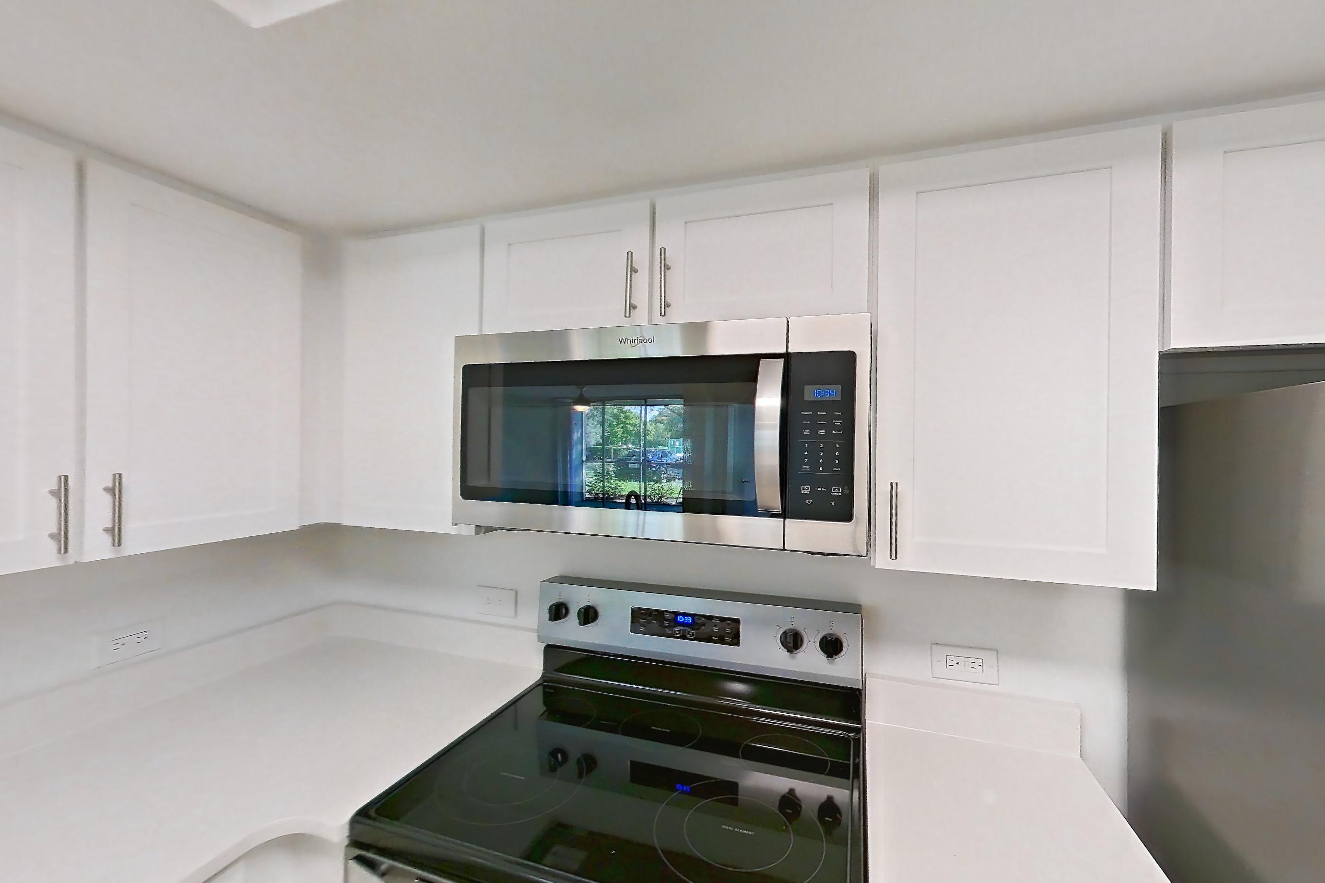 Kitchen with dishwasher, electric range, light countertops, light stone countertops, light tile flooring, microwave, oven/range, and stainless steel appliances, Apartment 09-12244 at Sabal Pointe