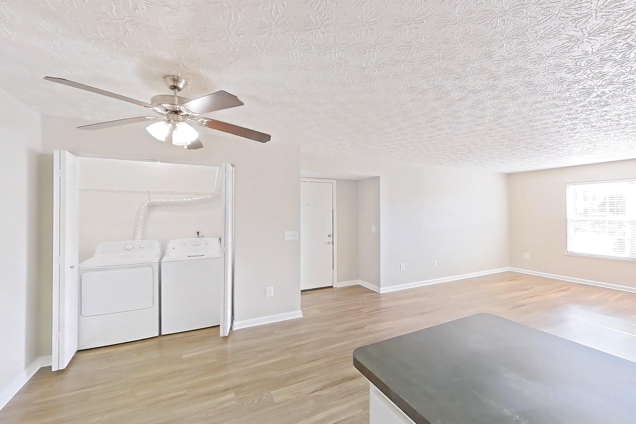 Kitchen with black appliances, dark countertops, dishwasher, electric range, in-unit laundry, light countertops, light wood-finish flooring, microwave, oven/range, refrigerator, and stainless steel appliances, Apartment 2728CLD at The Gardens Columbus