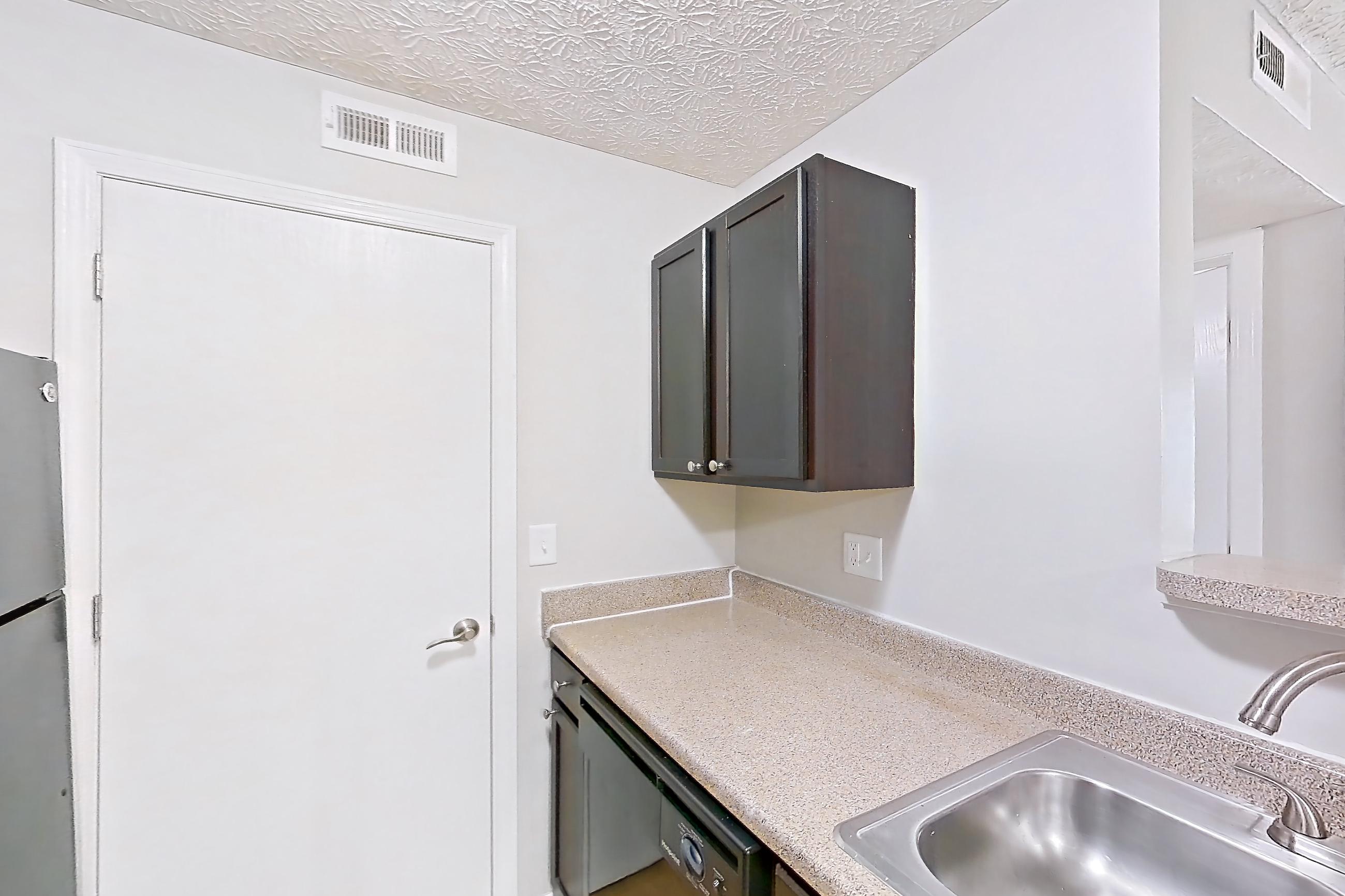 Kitchen with black appliances, dishwasher, electric range, in-unit laundry, light countertops, light wood-finish flooring, microwave, oven/range, and refrigerator, Apartment 3757SLC at The Gardens Columbus