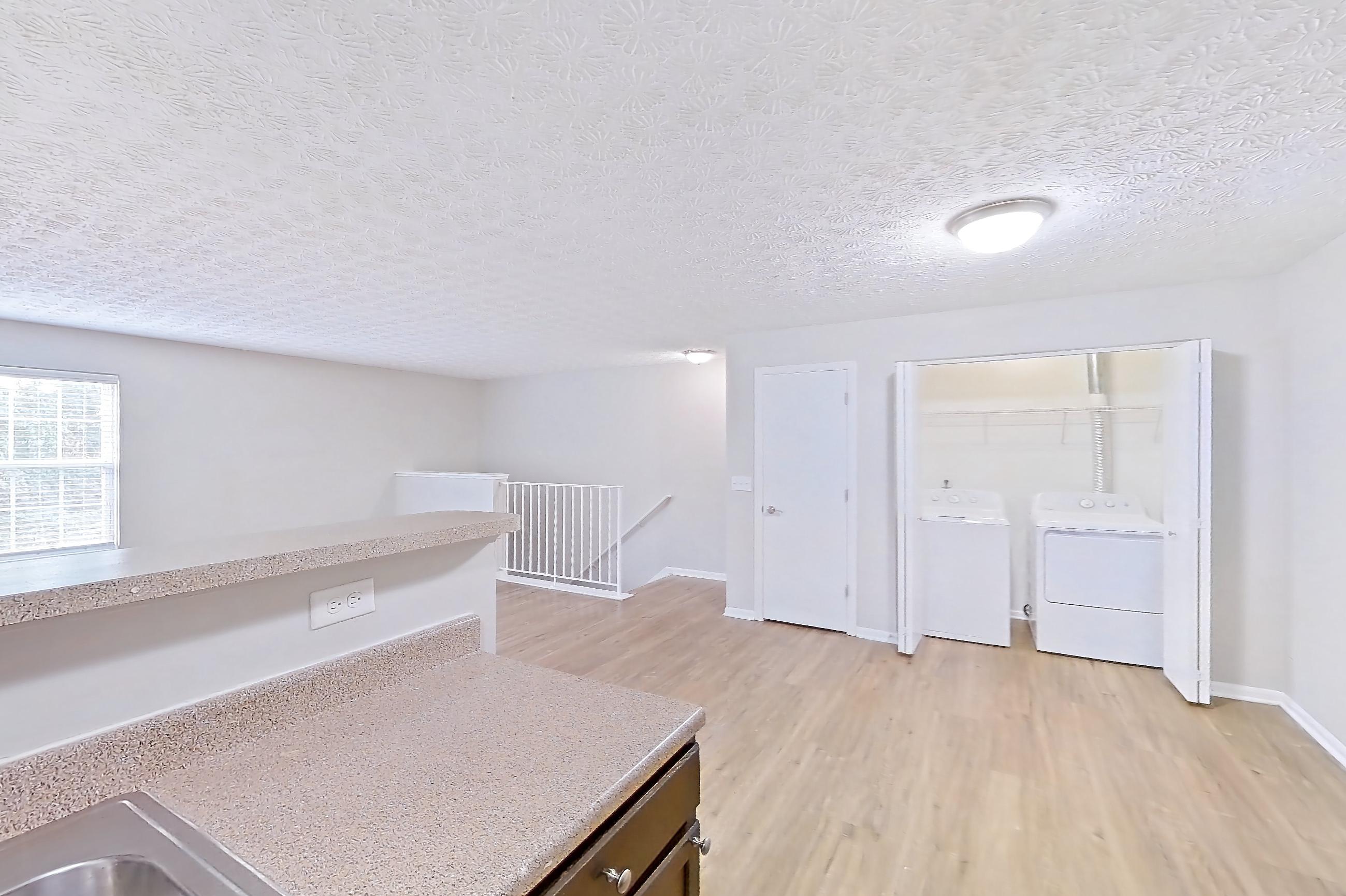 Kitchen with black appliances, dishwasher, electric range, in-unit laundry, light countertops, light wood-finish flooring, microwave, oven/range, and refrigerator, Apartment 3757SLC at The Gardens Columbus