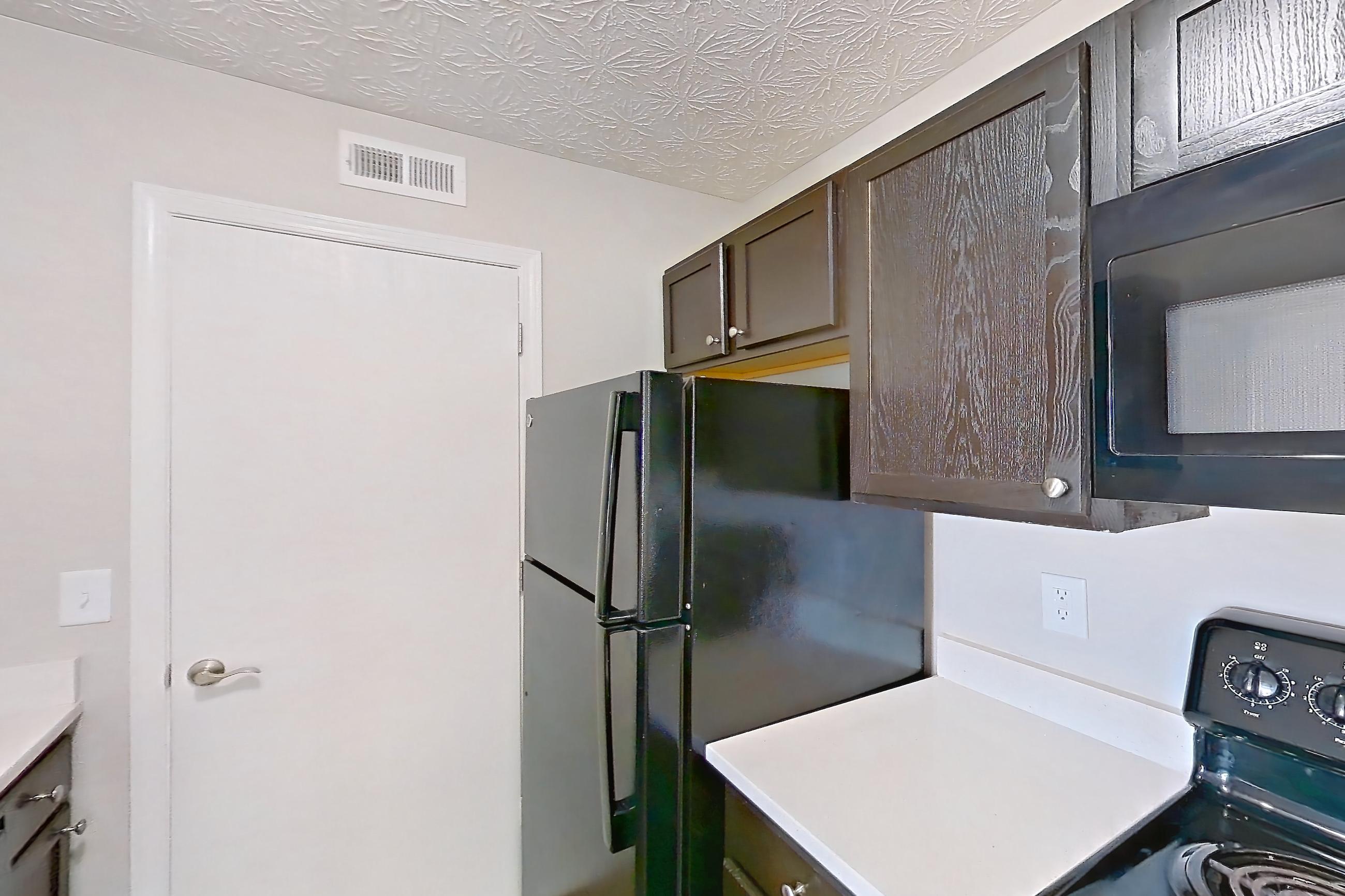 Kitchen with black appliances, dishwasher, electric range, light countertops, light stone countertops, light wood-finish flooring, microwave, oven/range, and refrigerator, Apartment 3152BLD at The Gardens Columbus