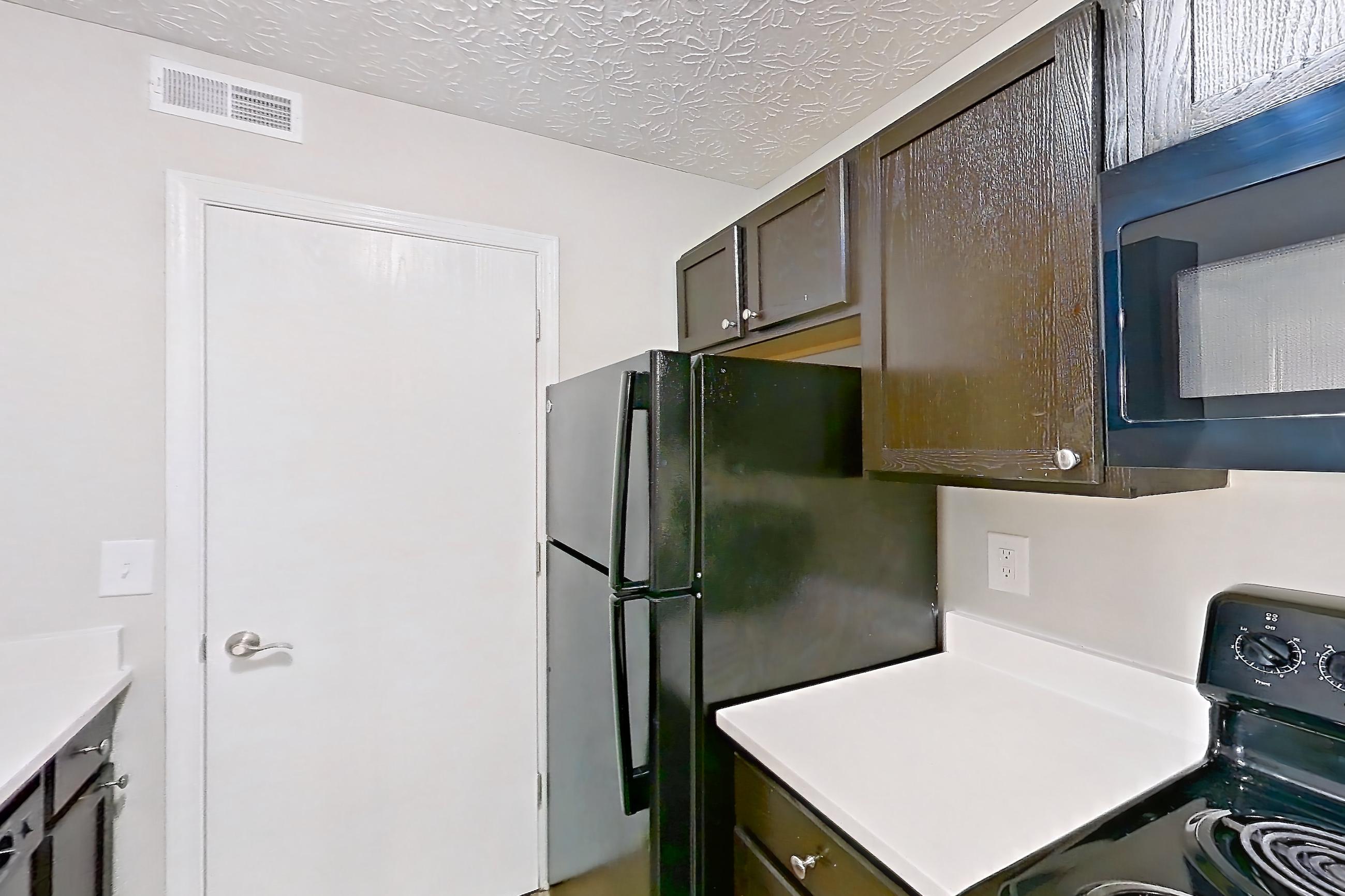 Kitchen with black appliances, dishwasher, electric range, light countertops, light wood-finish flooring, microwave, oven/range, refrigerator, and stainless steel appliances, Apartment 3642CCW at The Gardens Columbus