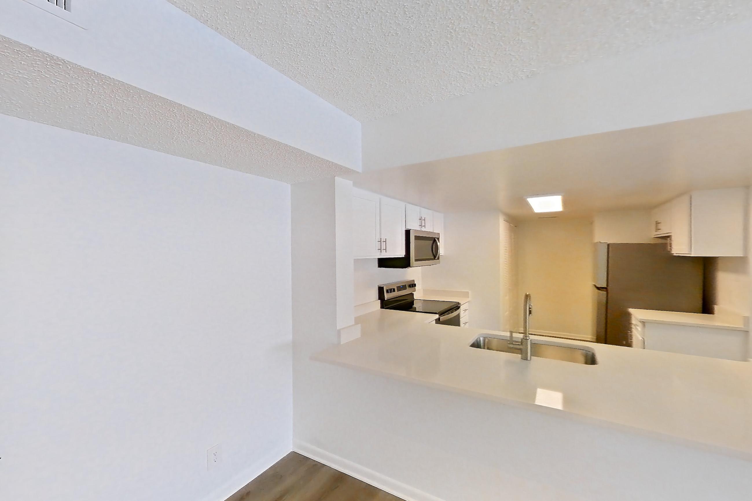 Living space with electric range, light countertops, light wood-finish flooring, oven/range, refrigerator, and stainless steel appliances, Apartment 11-023 at The Reserve at Ashley Lake