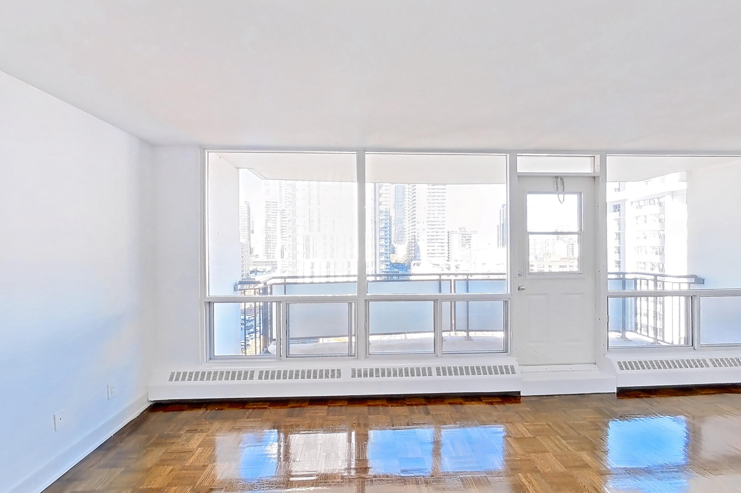 Living room with baseboard heating, dark wood-finish flooring, dishwasher, electric range, light countertops, light wood-finish flooring, oven/range, parquet flooring, refrigerator, and stainless steel appliances, Apartment 1-1611 at Village Green