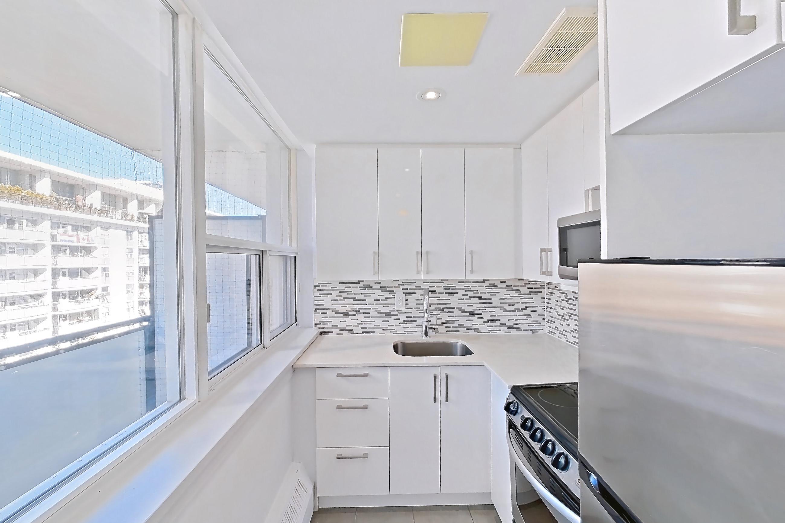 Kitchen with baseboard heating, electric range, light stone countertops, light tile flooring, light wood-finish flooring, oven/range, parquet flooring, refrigerator, and stainless steel appliances, Apartment 1-1714 at Village Green