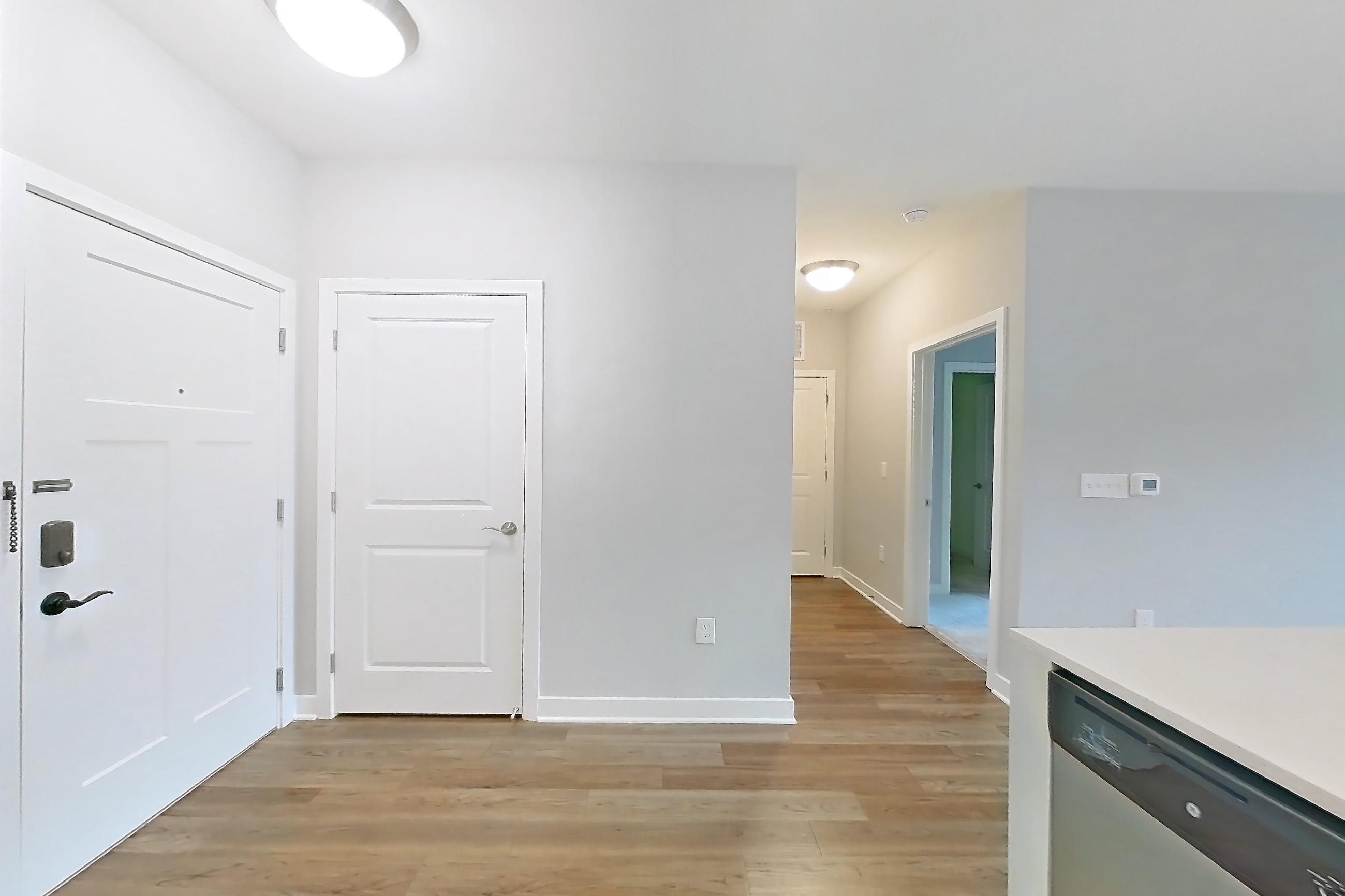 Kitchen with dishwasher, electric range, light countertops, light stone countertops, light wood-finish flooring, microwave, oven/range, refrigerator, and stainless steel appliances, Apartment 15206 at Briggs & Union