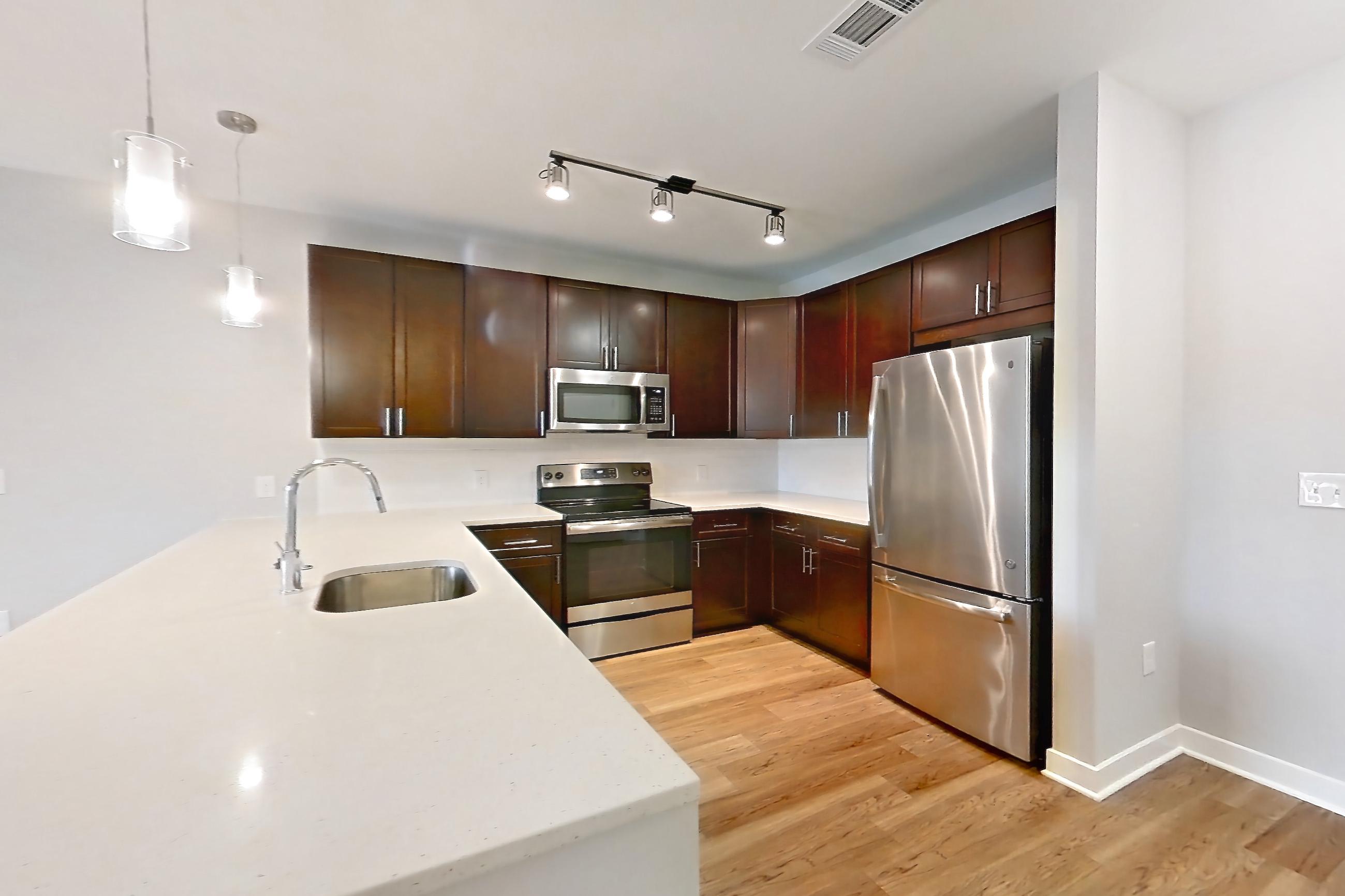 Living space with electric range, light countertops, light stone countertops, light wood-finish flooring, microwave, oven/range, and stainless steel appliances, Apartment 15206 at Briggs & Union
