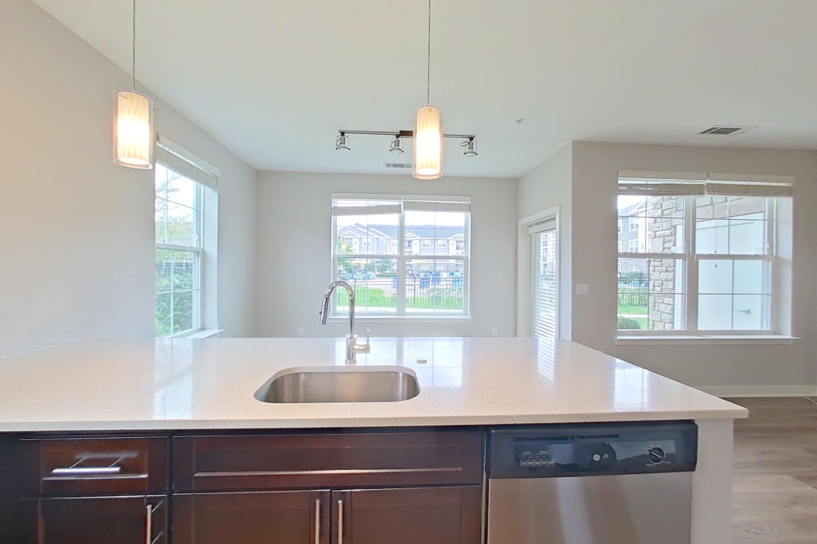 Kitchen with dishwasher, electric range, light countertops, light stone countertops, light wood-finish flooring, microwave, oven/range, refrigerator, and stainless steel appliances, Apartment 10102 at Briggs & Union