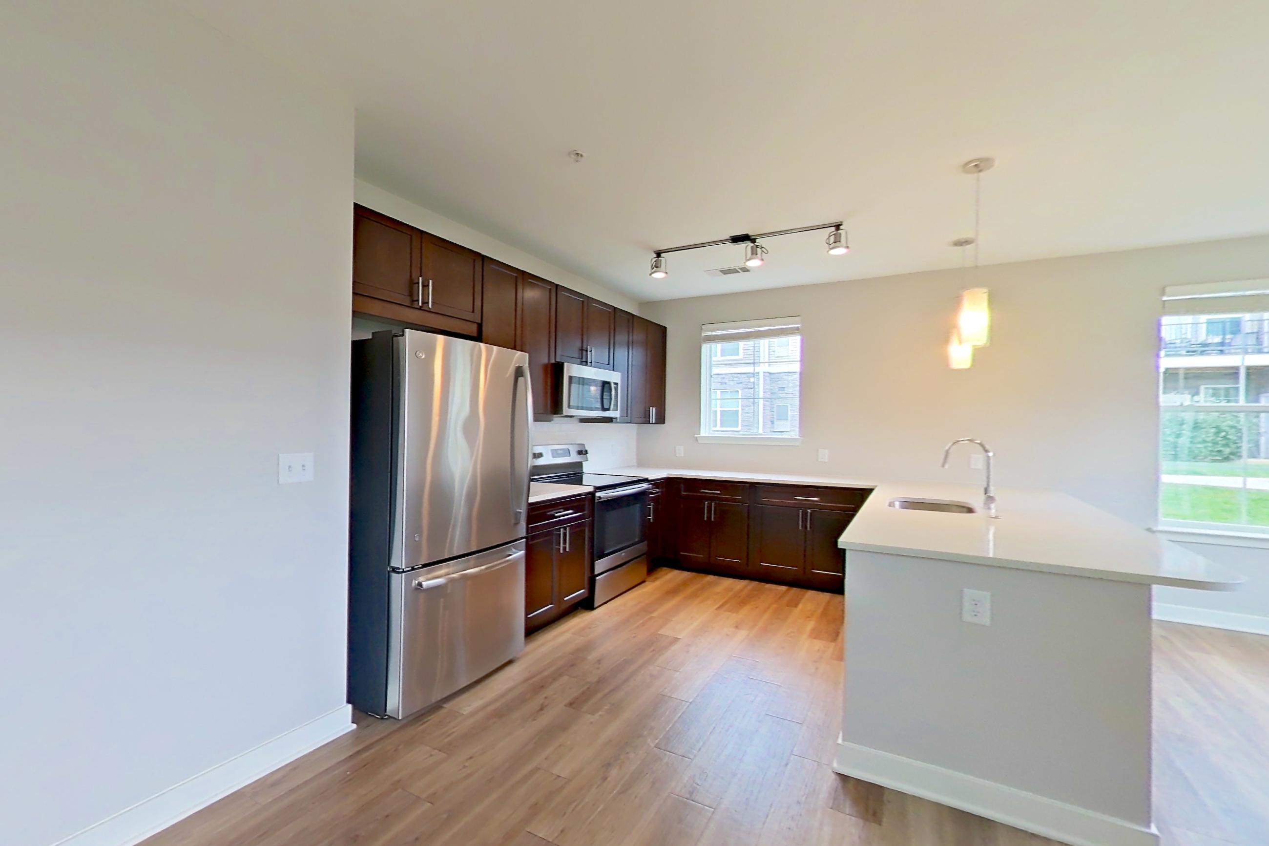 Living room with electric range, light countertops, light wood-finish flooring, oven/range, refrigerator, and stainless steel appliances, Apartment 10102 at Briggs & Union