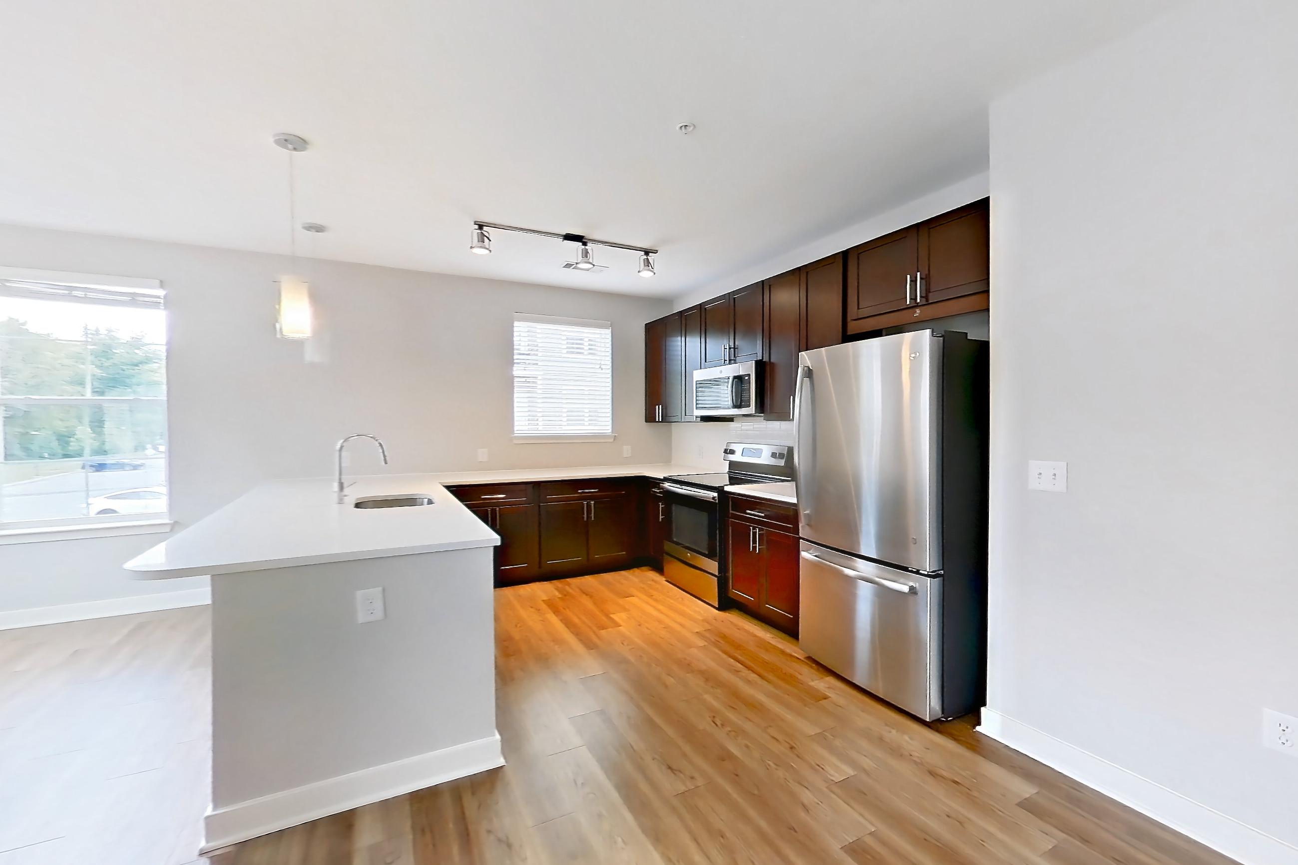 Living room with electric range, light countertops, light wood-finish flooring, oven/range, refrigerator, and stainless steel appliances, Apartment 10201 at Briggs & Union