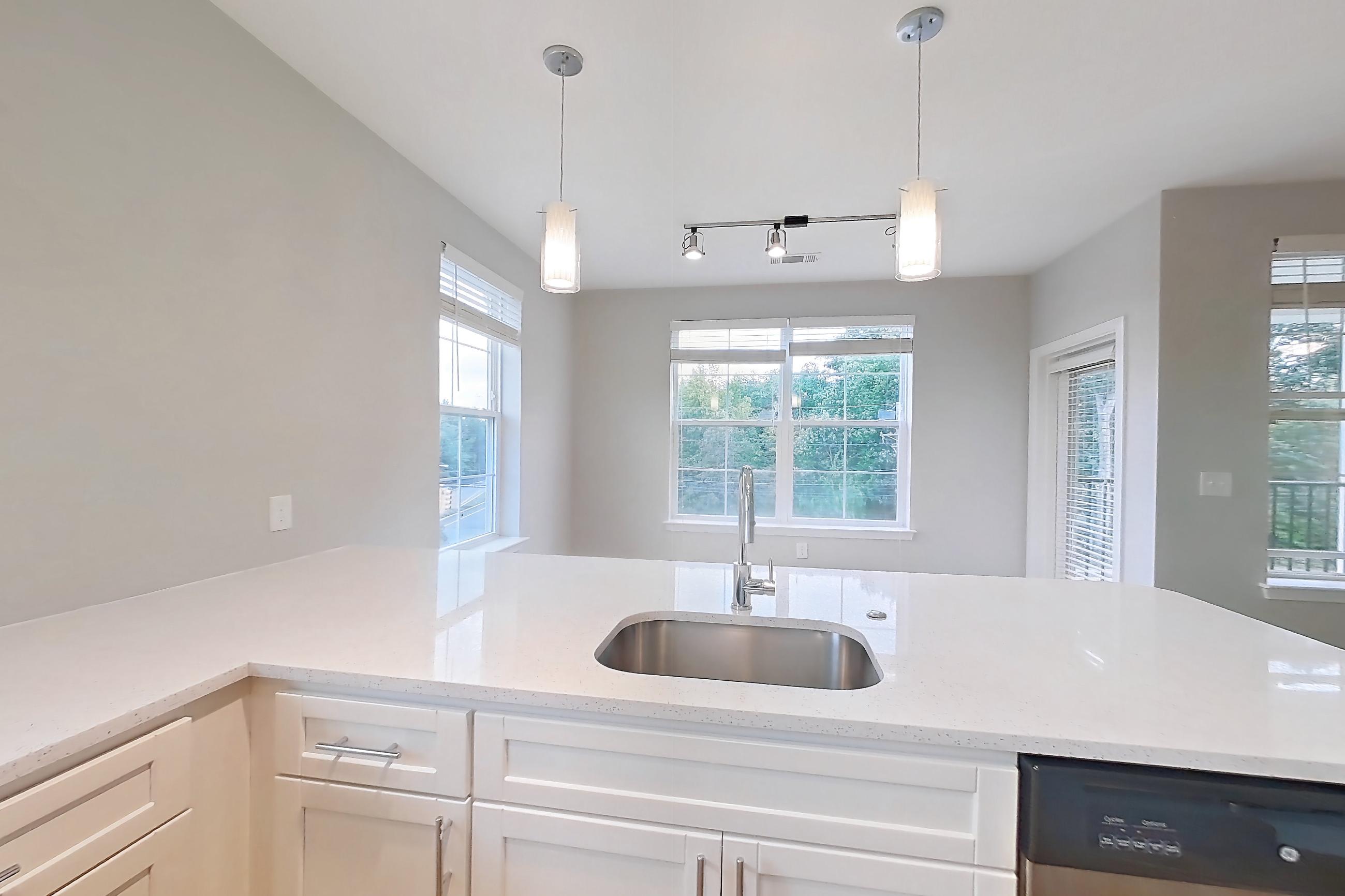 Kitchen with dishwasher, electric range, light countertops, light stone countertops, light wood-finish flooring, microwave, oven/range, refrigerator, and stainless steel appliances, Apartment 1302 at Briggs & Union