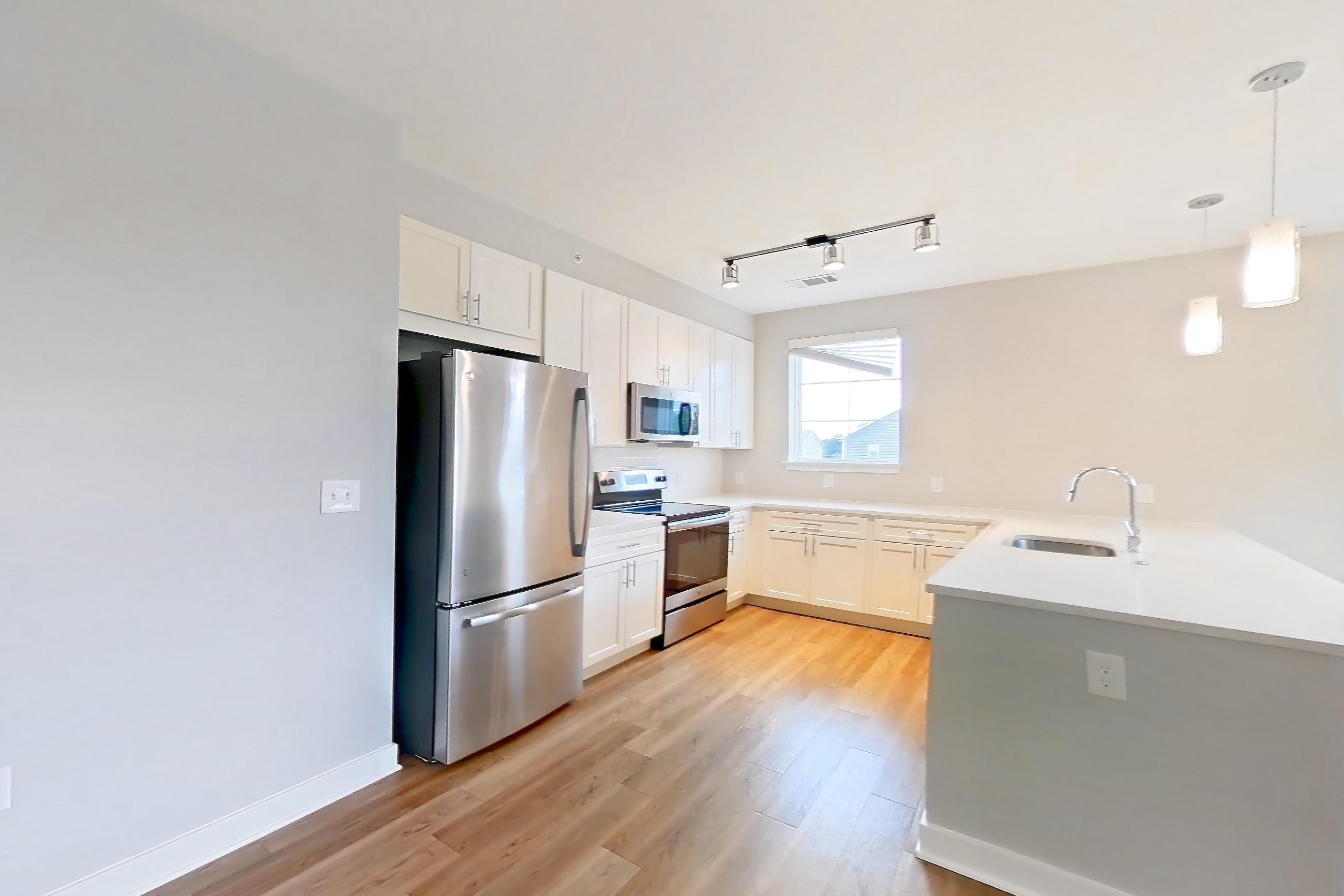 Living room with electric range, light countertops, light stone countertops, light wood-finish flooring, oven/range, refrigerator, and stainless steel appliances, Apartment 1302 at Briggs & Union