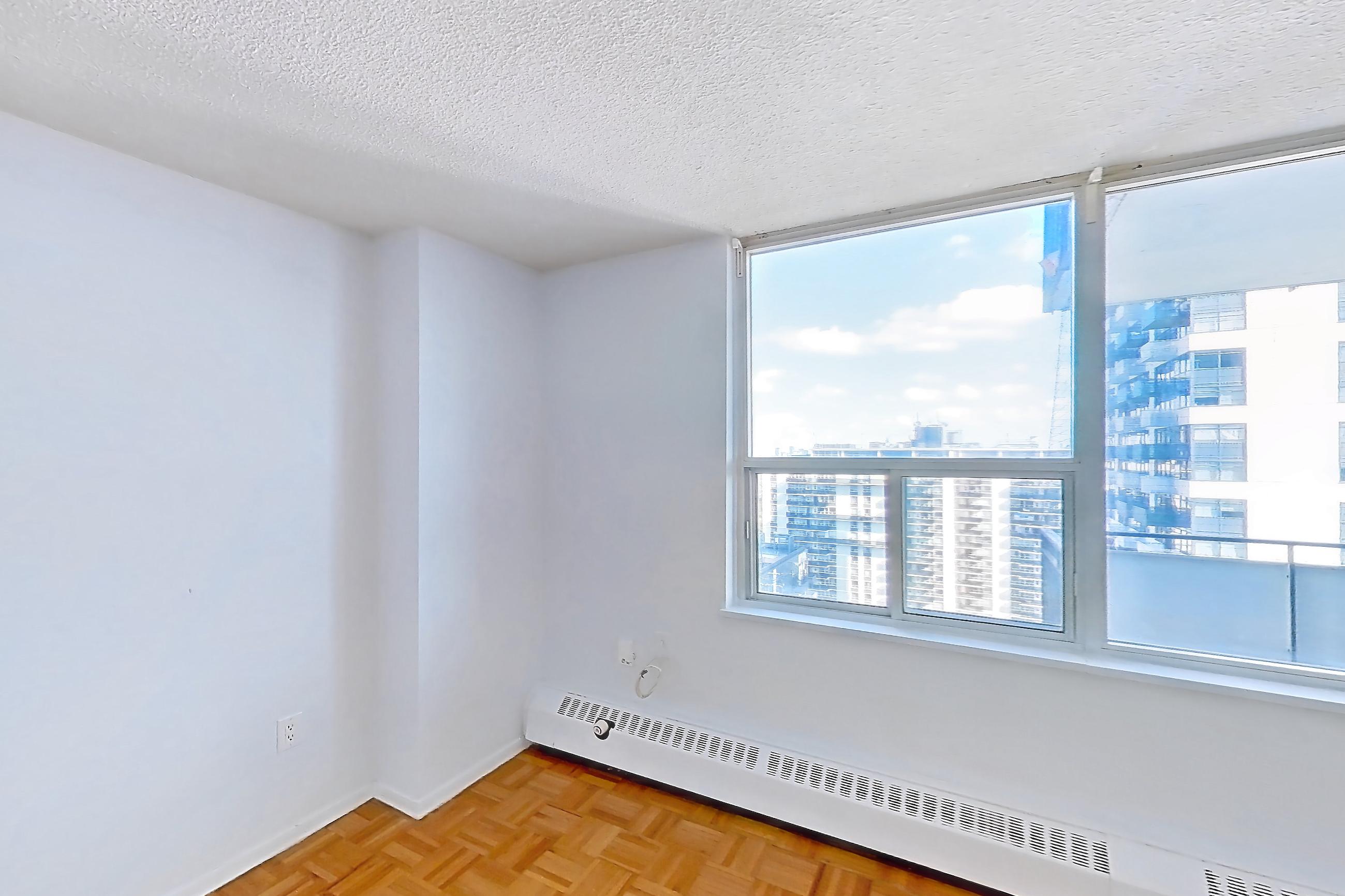 Living room with baseboard heating, light wood-finish flooring, parquet flooring, refrigerator, and white appliances, Apartment 2507 at 77 Davisville