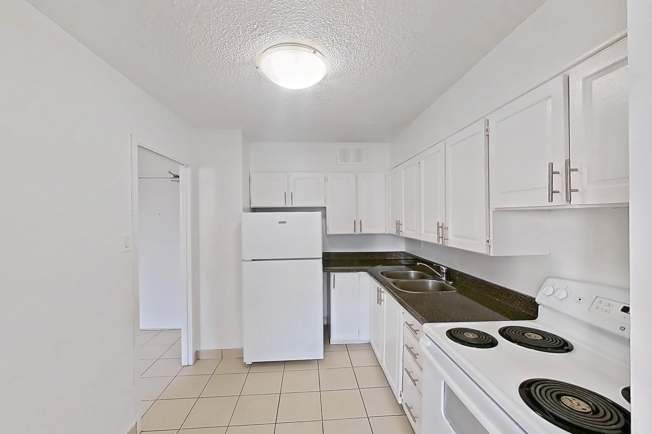 Kitchen with dark countertops, electric range, light tile flooring, light wood-finish flooring, oven/range, parquet flooring, refrigerator, and white appliances, Apartment 1611 at 77 Davisville