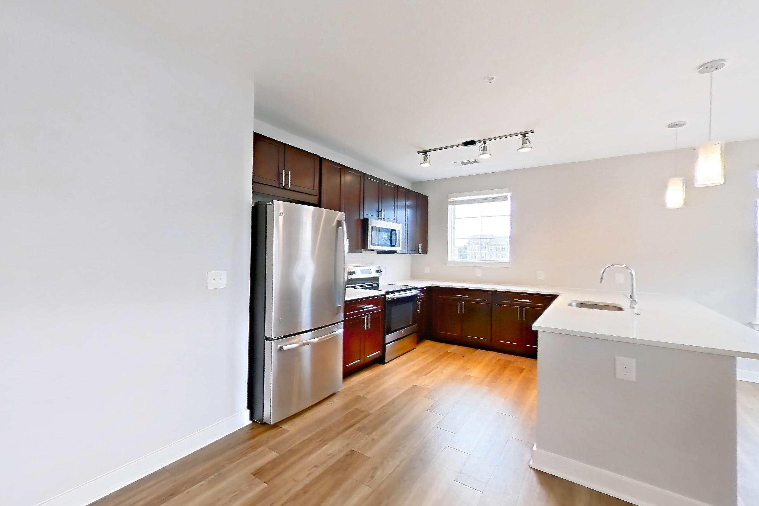 Living room with electric range, light countertops, light wood-finish flooring, microwave, oven/range, refrigerator, and stainless steel appliances, Apartment 2209 at Briggs & Union
