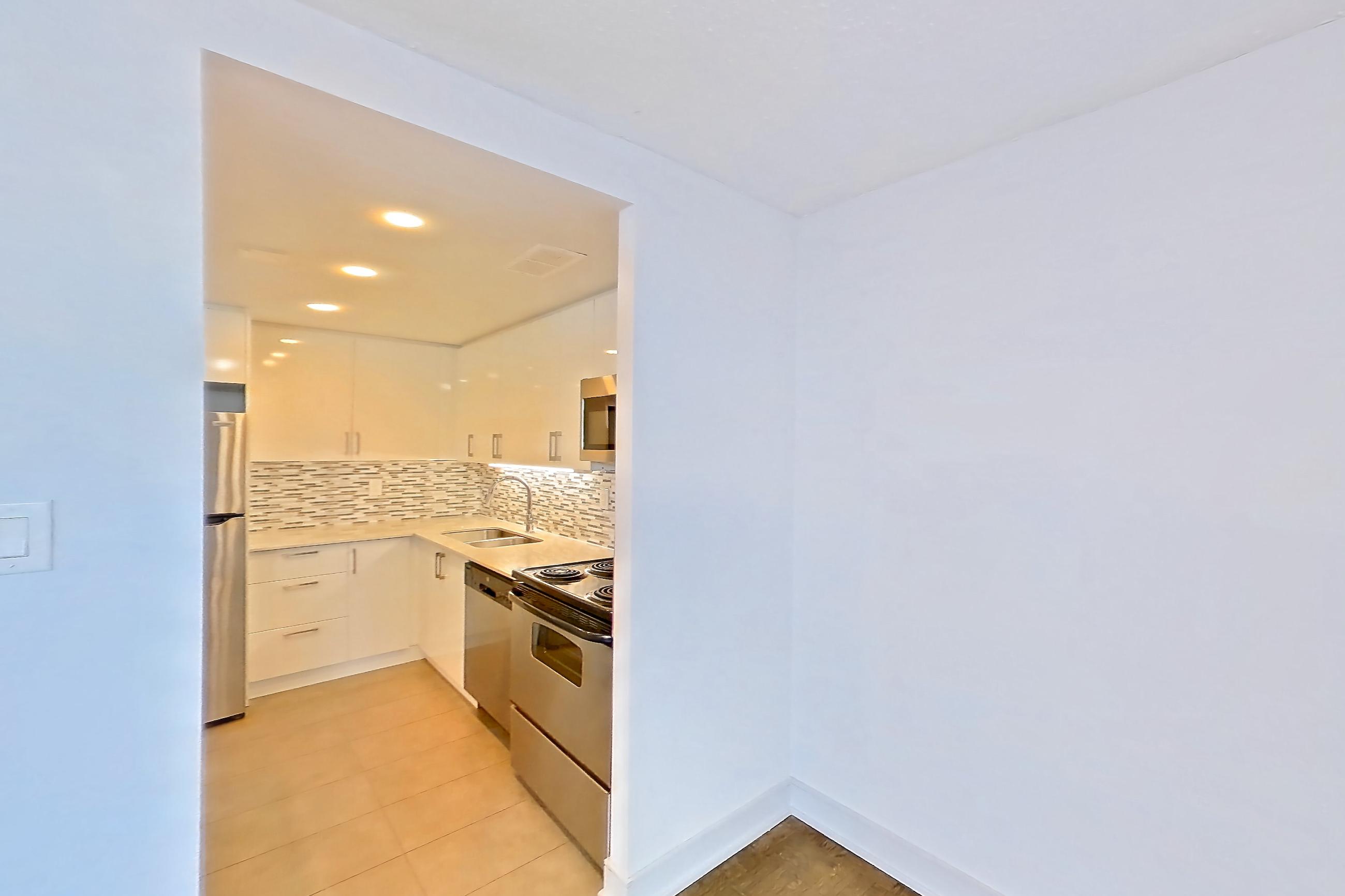 Living room with baseboard heating, dishwasher, electric range, light countertops, light wood-finish flooring, oven/range, parquet flooring, refrigerator, and stainless steel appliances, Apartment 2209 at 77 Davisville