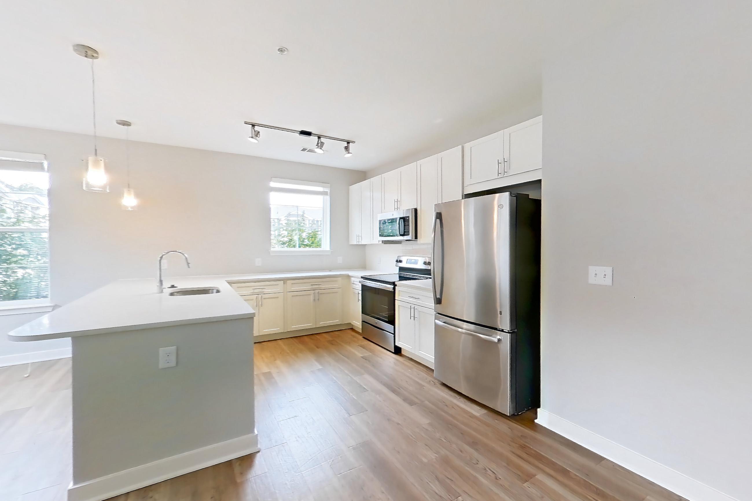 Living room with electric range, light countertops, light wood-finish flooring, oven/range, refrigerator, and stainless steel appliances, Apartment 14101 at Briggs & Union