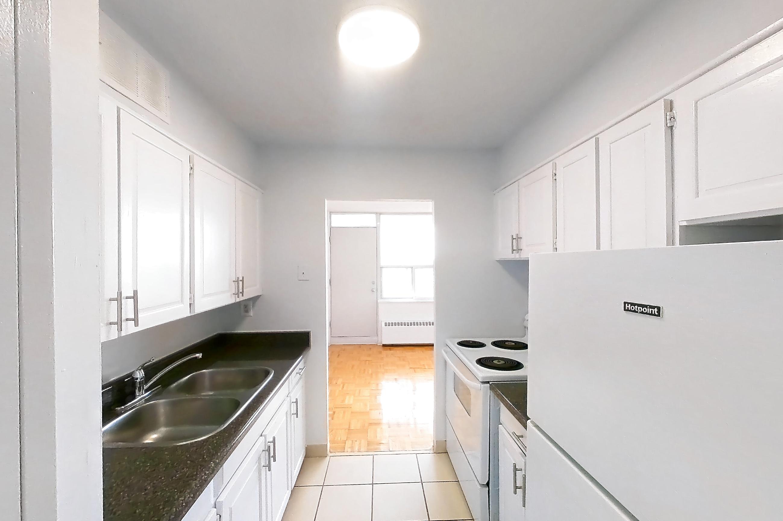 Kitchen with dark countertops, electric range, light tile flooring, oven/range, refrigerator, and white appliances, Apartment 1018 at 77 Davisville