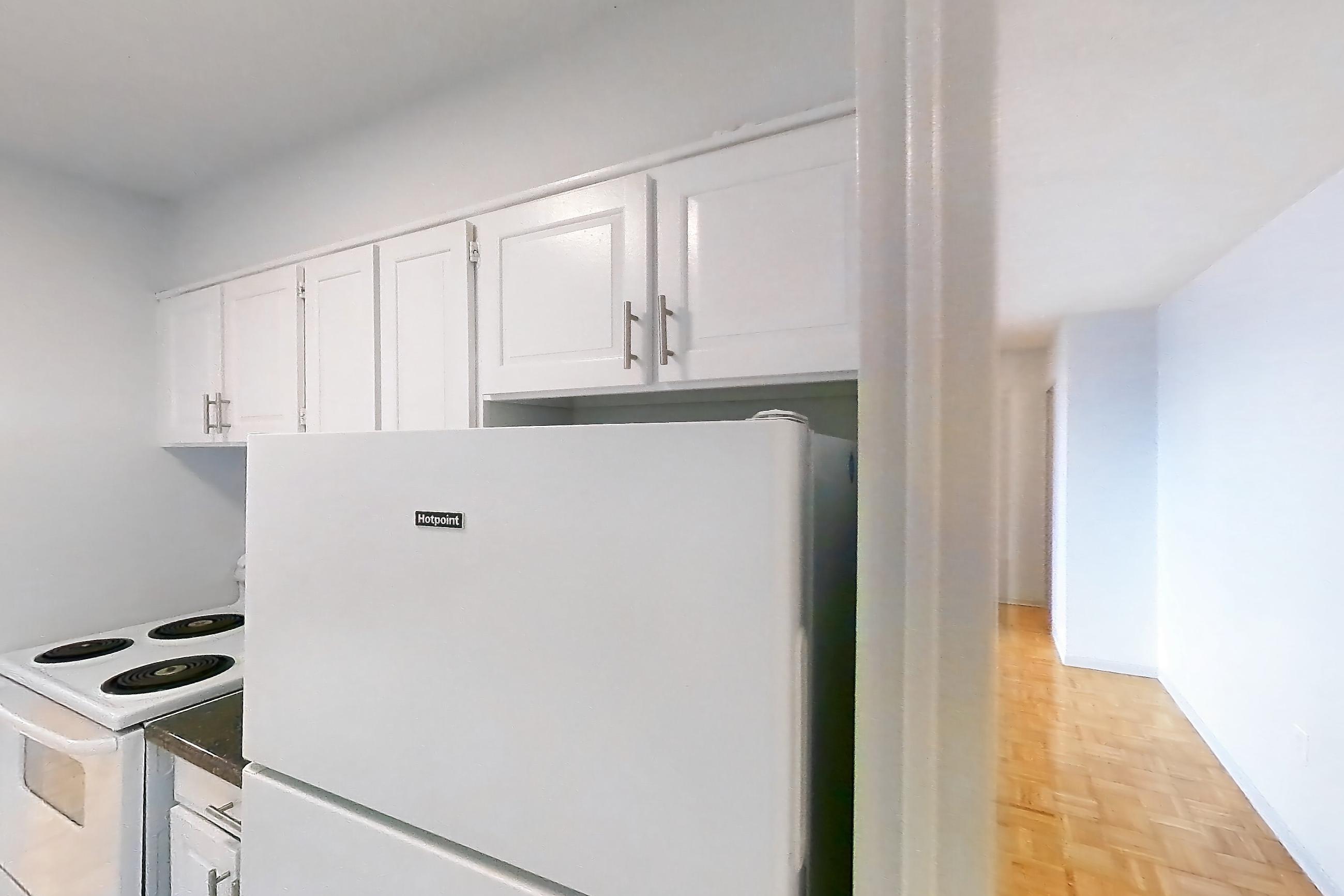 Kitchen with dark countertops, electric range, light tile flooring, oven/range, refrigerator, and white appliances, Apartment 1018 at 77 Davisville