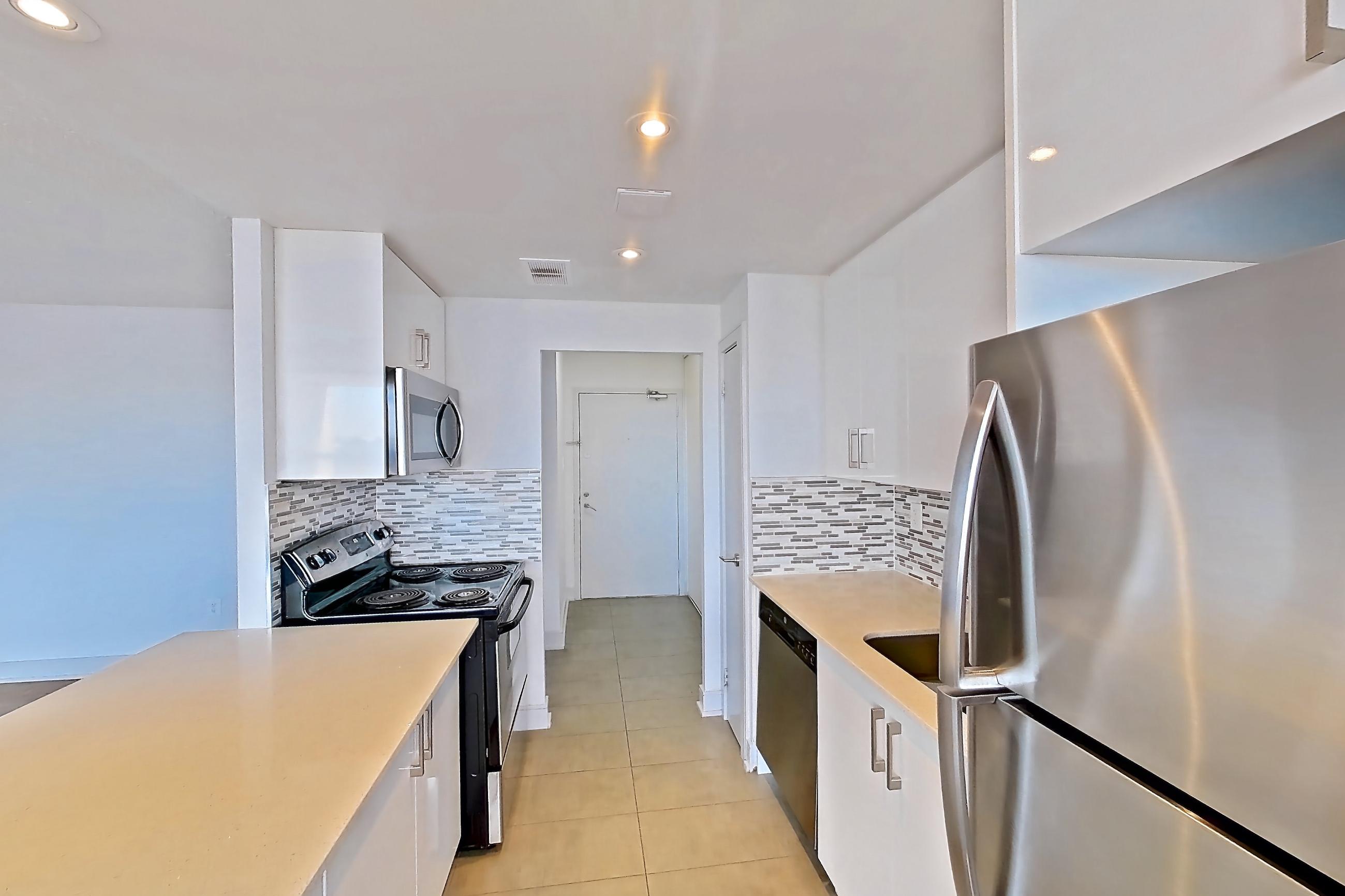 Kitchen with baseboard heating, dishwasher, electric range, light countertops, light tile flooring, light wood-finish flooring, oven/range, refrigerator, and stainless steel appliances, Apartment 0918 at 77 Davisville