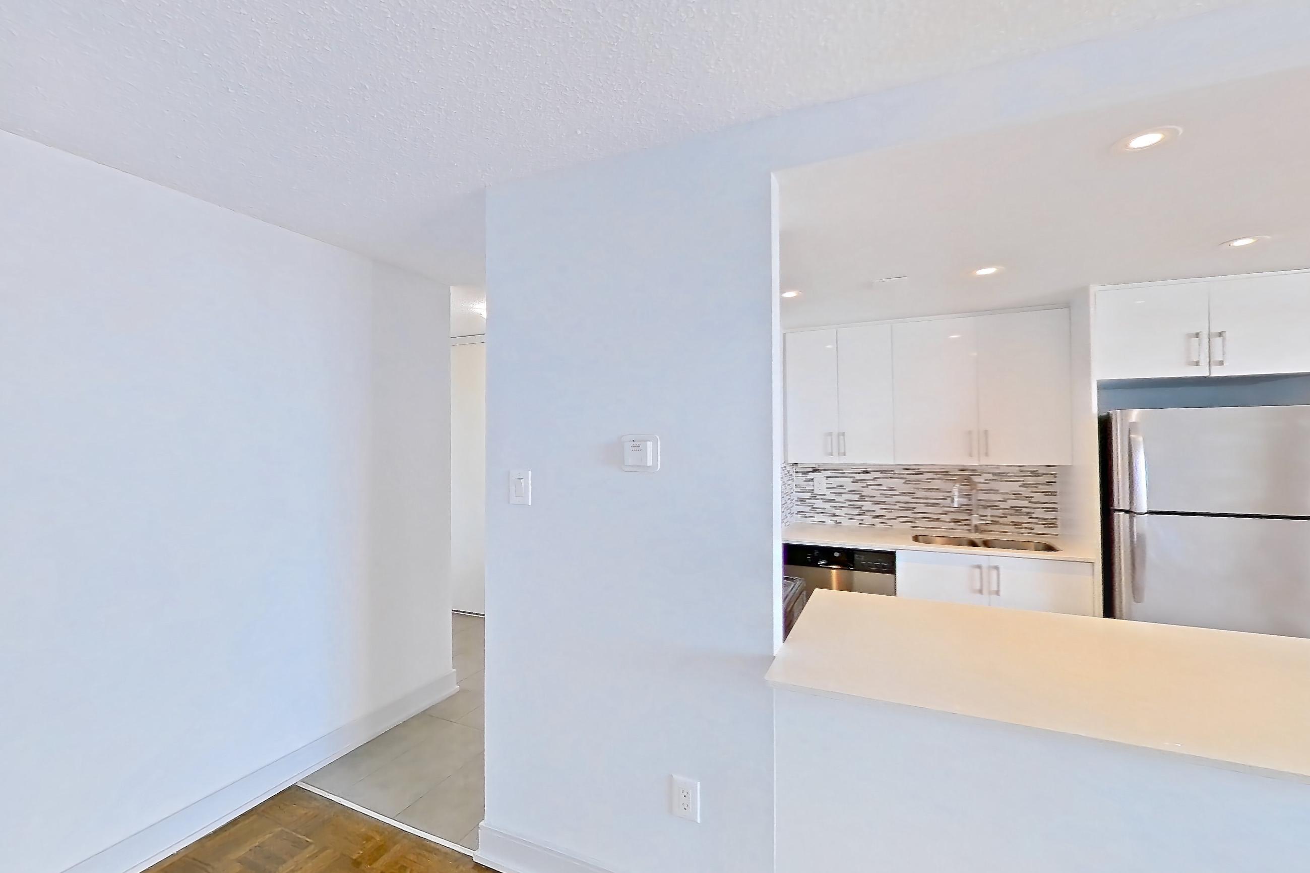 Living room with baseboard heating, dishwasher, light wood-finish flooring, parquet flooring, refrigerator, and stainless steel appliances, Apartment 0918 at 77 Davisville