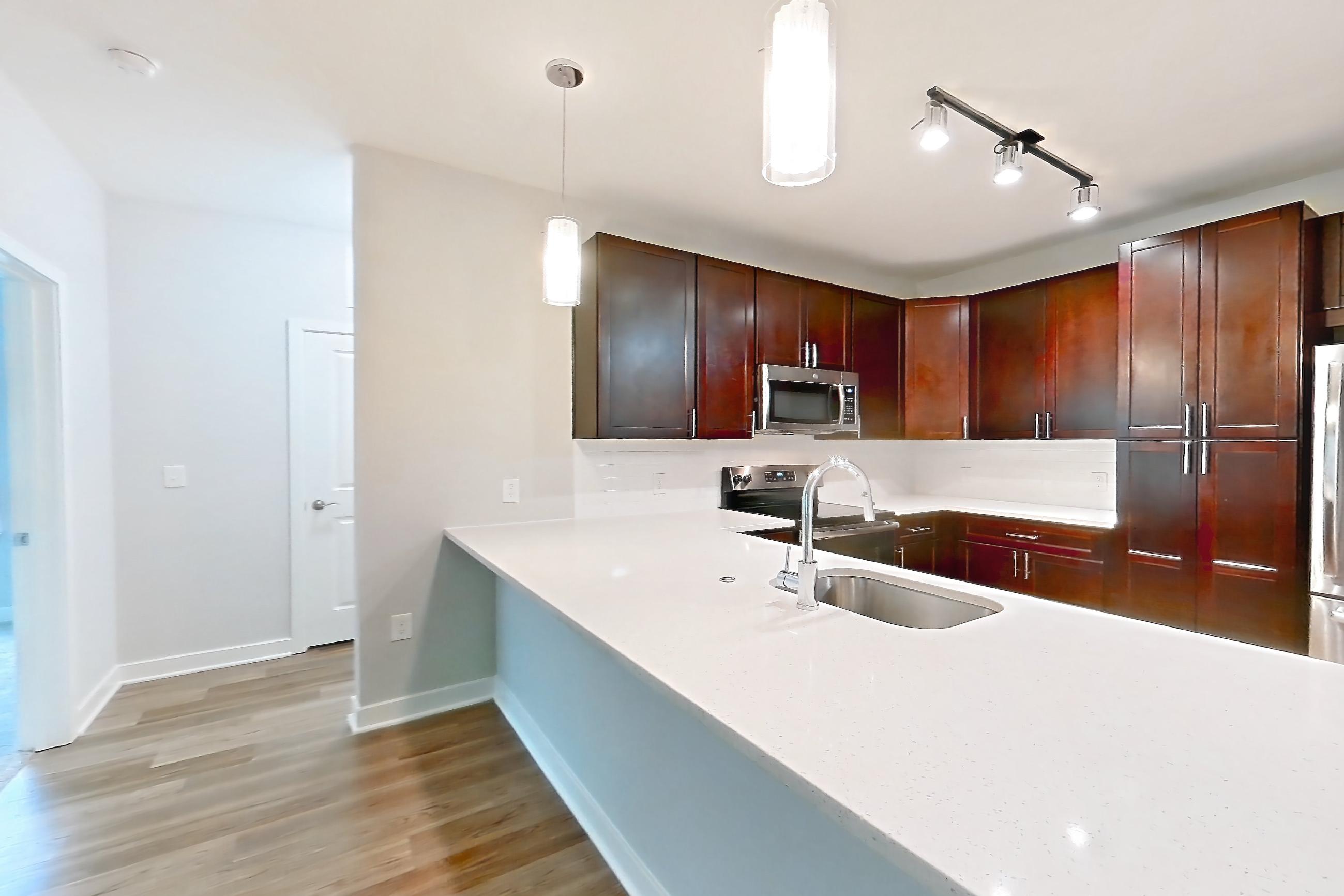 Living space with dark wood-finish flooring, light countertops, and light wood-finish flooring, Apartment 17105 at Briggs & Union