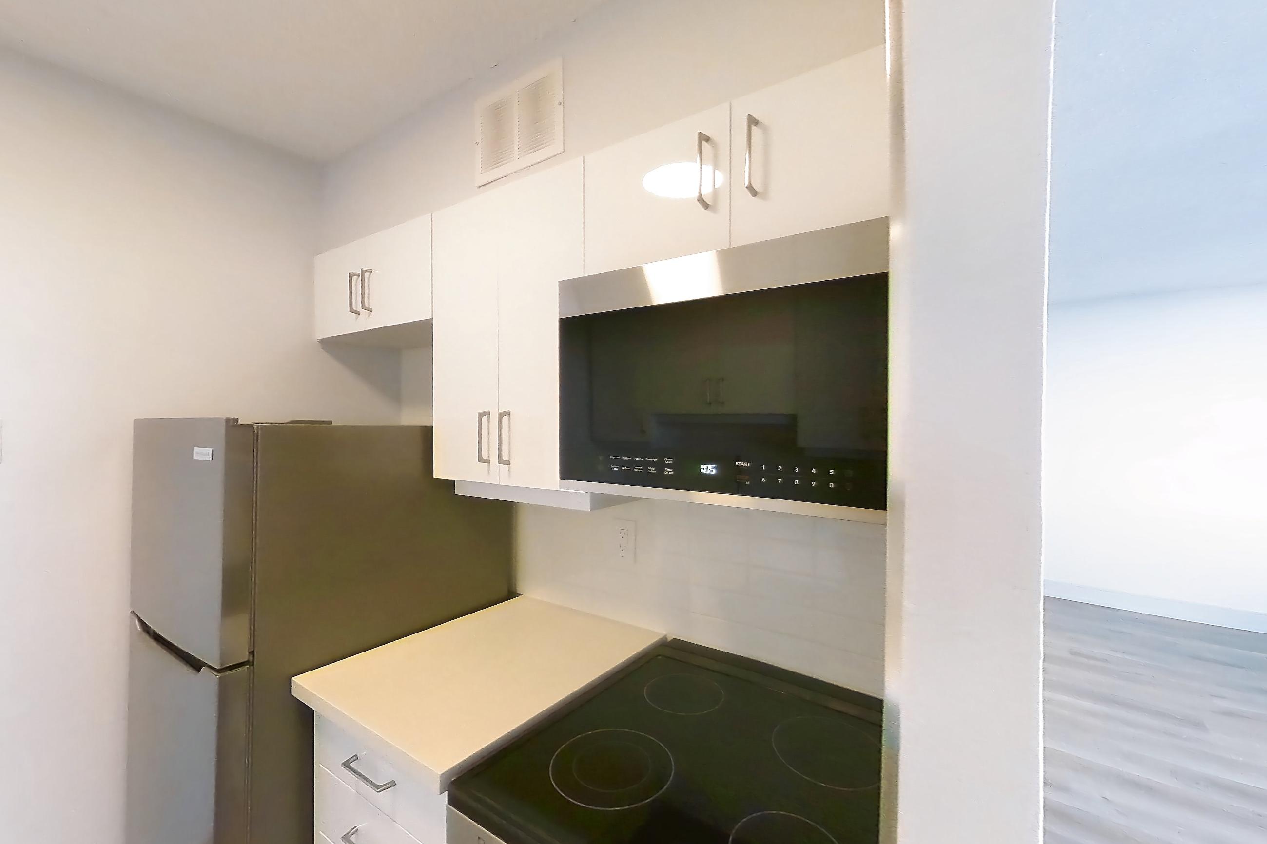 Kitchen with baseboard heating, dishwasher, electric range, light countertops, light stone countertops, light wood-finish flooring, oven/range, refrigerator, and stainless steel appliances, Apartment 2805 at 77 Davisville