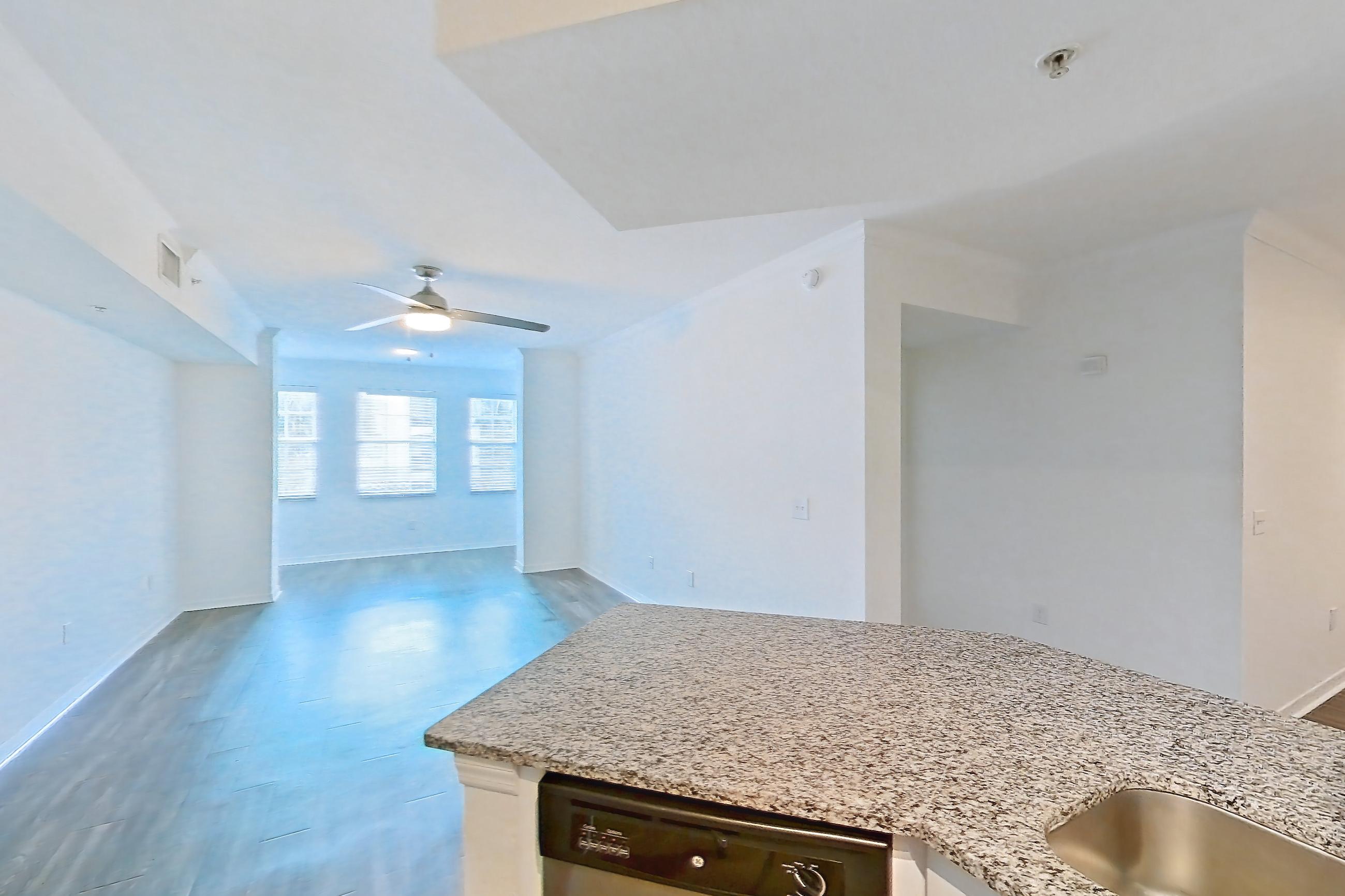 Kitchen with dark wood-finish flooring, dishwasher, electric range, light countertops, light stone countertops, light wood-finish flooring, microwave, oven/range, and stainless steel appliances, Apartment 12-204 at Solano at Miramar