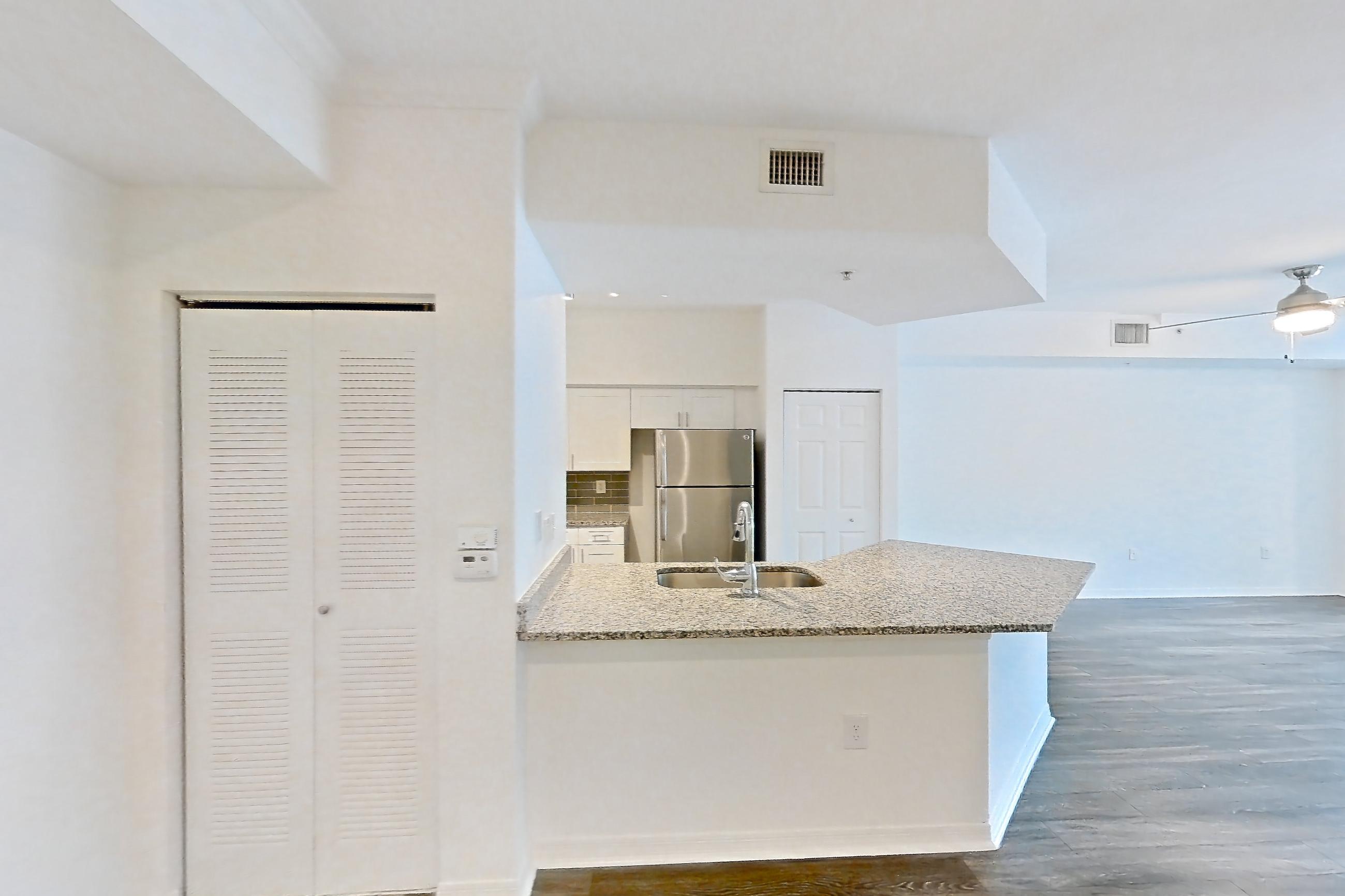 Living space with dark wood-finish flooring, refrigerator, and stainless steel appliances, Apartment 12-204 at Solano at Miramar