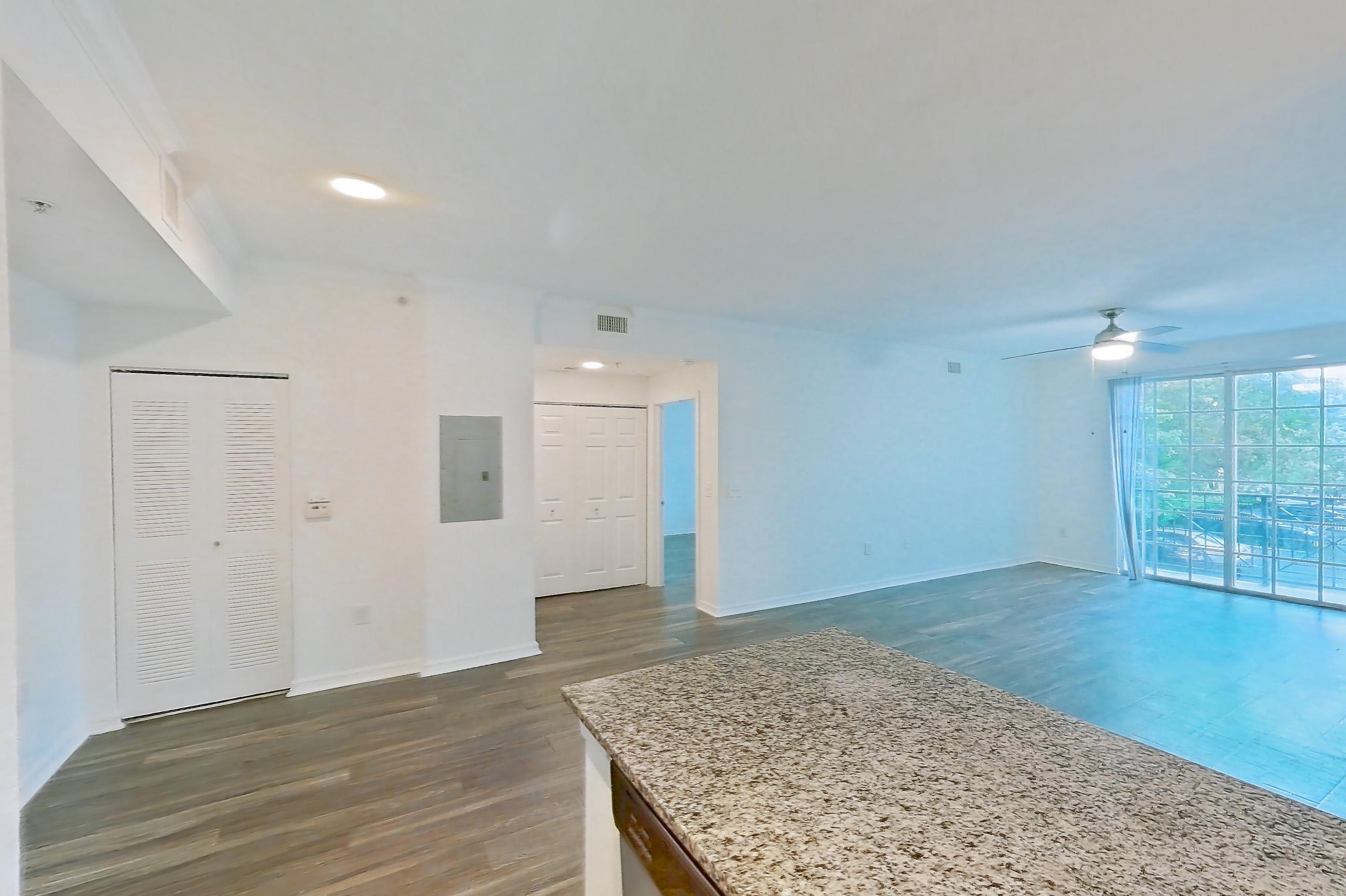 Kitchen with dishwasher, electric range, light countertops, light stone countertops, light wood-finish flooring, oven/range, refrigerator, and stainless steel appliances, Apartment 01-208 at Solano at Miramar