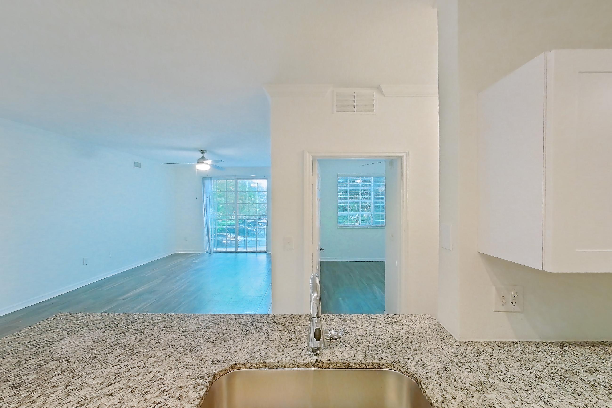 Kitchen with dishwasher, electric range, light countertops, light stone countertops, light wood-finish flooring, oven/range, refrigerator, and stainless steel appliances, Apartment 01-208 at Solano at Miramar