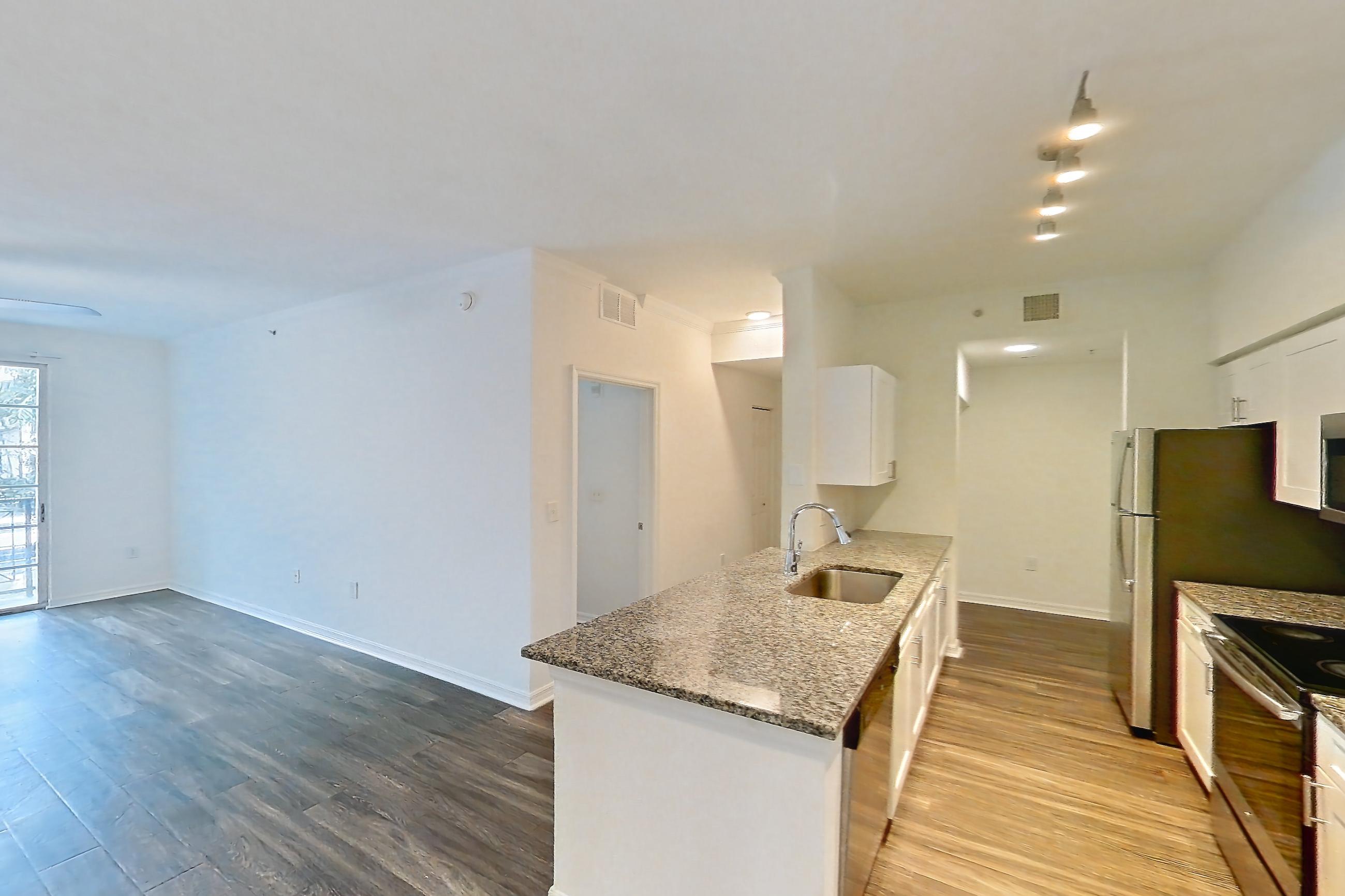 Living space with dark wood-finish flooring, dishwasher, electric range, light stone countertops, oven/range, refrigerator, and stainless steel appliances, Apartment 01-208 at Solano at Miramar
