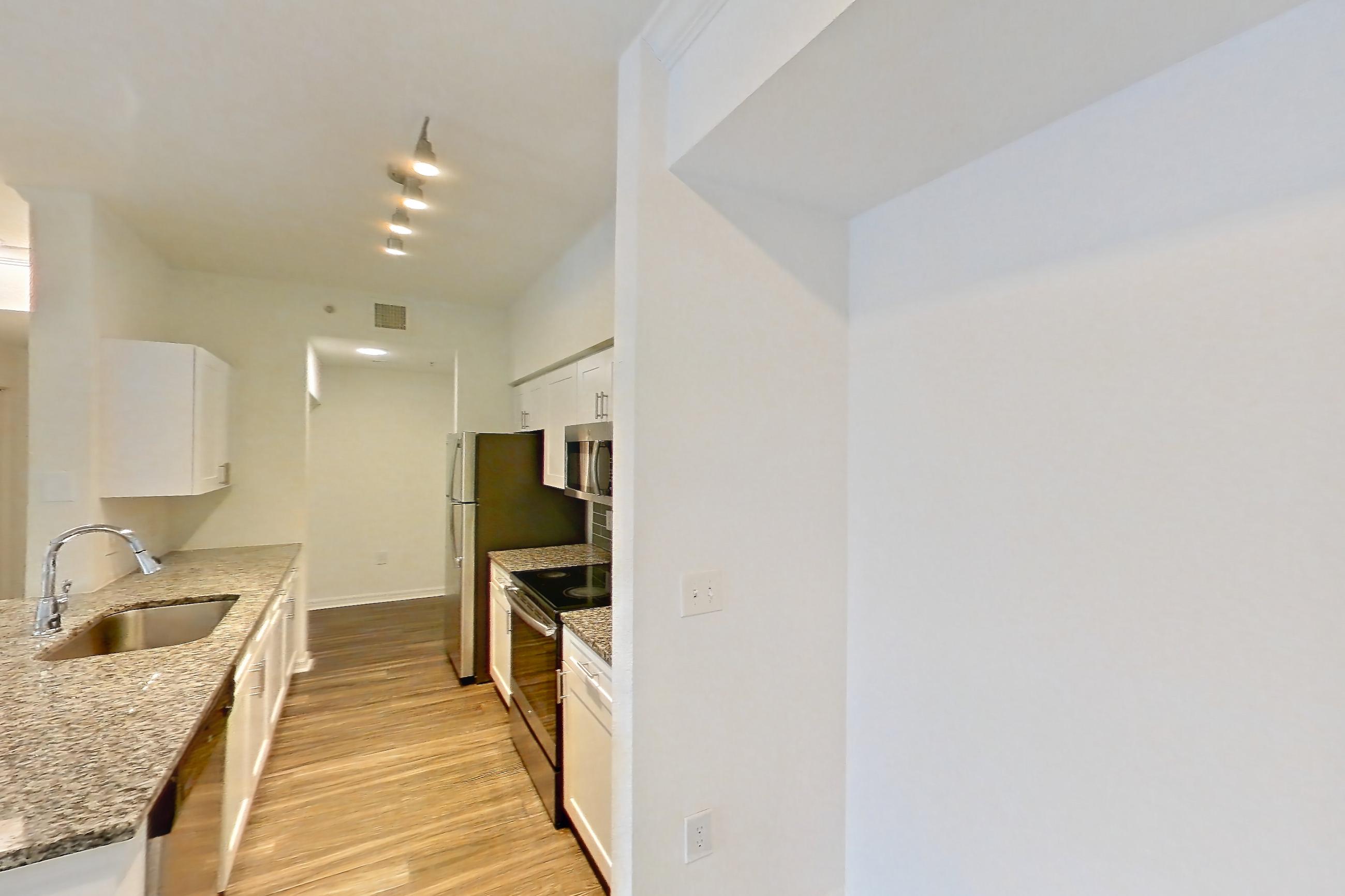Living space with dark wood-finish flooring, dishwasher, electric range, light stone countertops, oven/range, refrigerator, and stainless steel appliances, Apartment 01-208 at Solano at Miramar