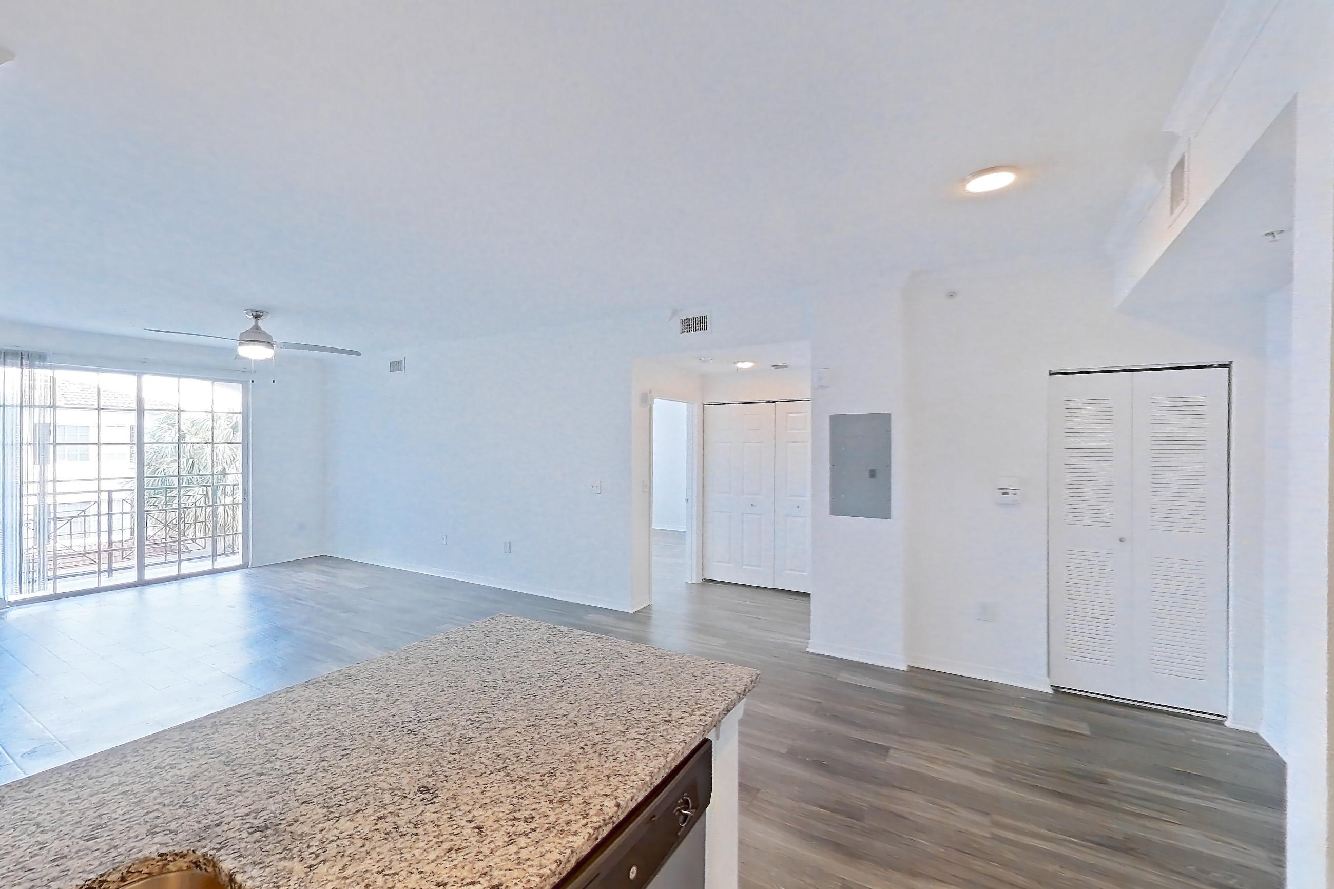 Kitchen with dishwasher, electric range, light countertops, light stone countertops, light wood-finish flooring, oven/range, refrigerator, and stainless steel appliances, Apartment 04-301 at Solano at Miramar