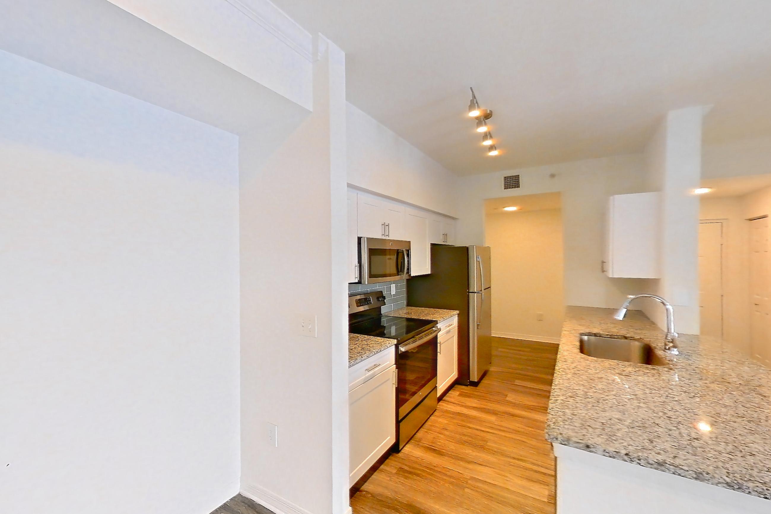 Main living space with dark wood-finish flooring, electric range, light stone countertops, light wood-finish flooring, oven/range, refrigerator, and stainless steel appliances, Apartment 04-301 at Solano at Miramar