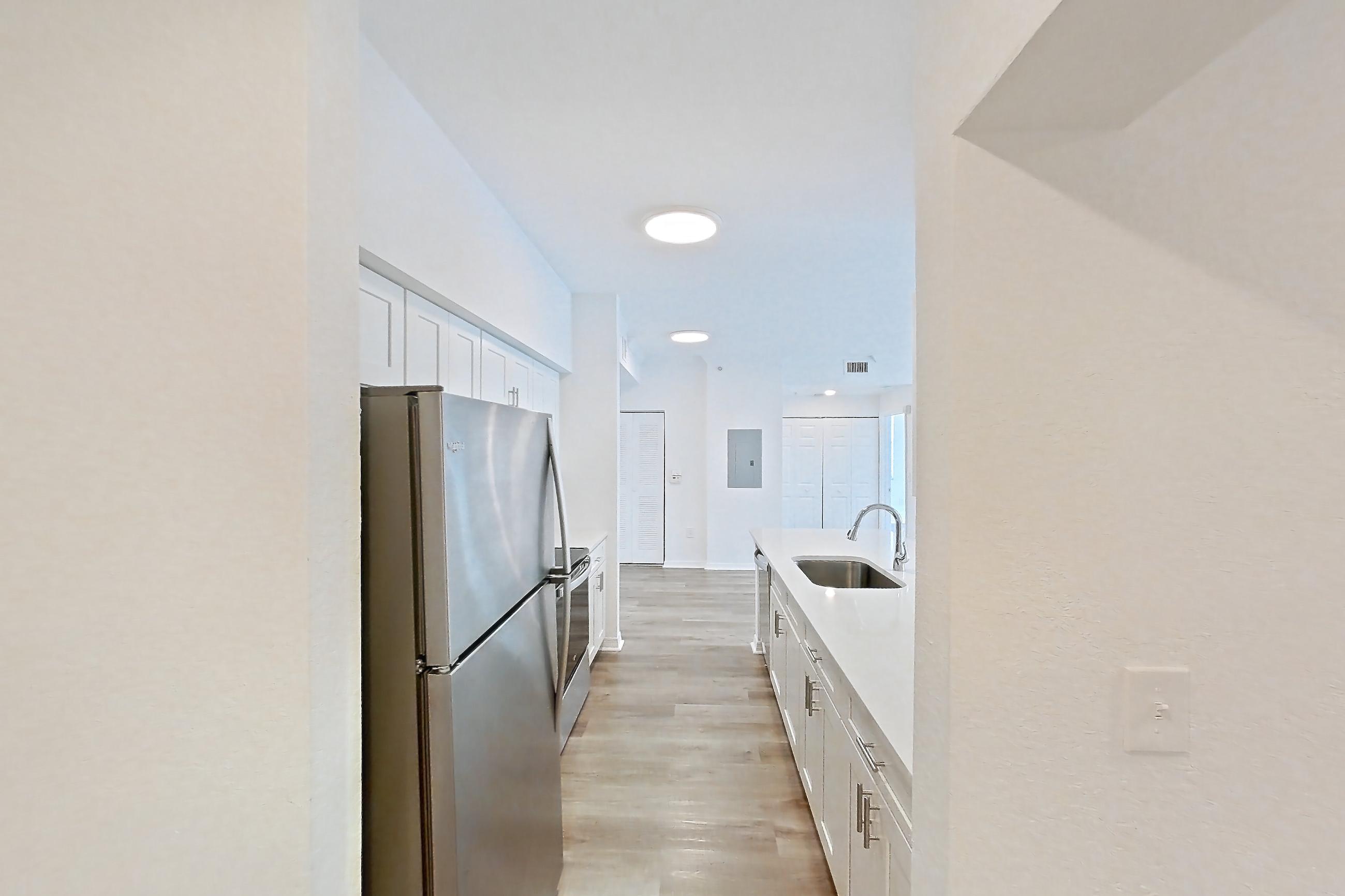 Entryway living space with kitchen island, light stone countertops, light wood-finish flooring, oven/range, refrigerator, and stainless steel appliances, Apartment 11-208 at Solano at Miramar