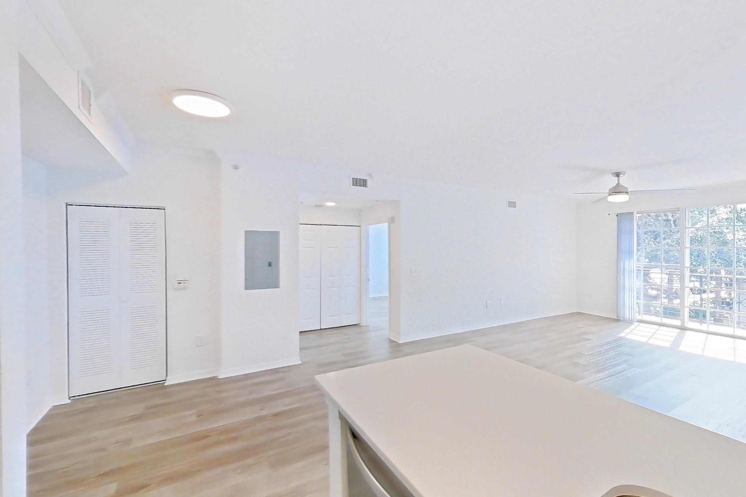 Kitchen with dishwasher, electric range, light countertops, light stone countertops, light wood-finish flooring, oven/range, refrigerator, and stainless steel appliances, Apartment 11-208 at Solano at Miramar
