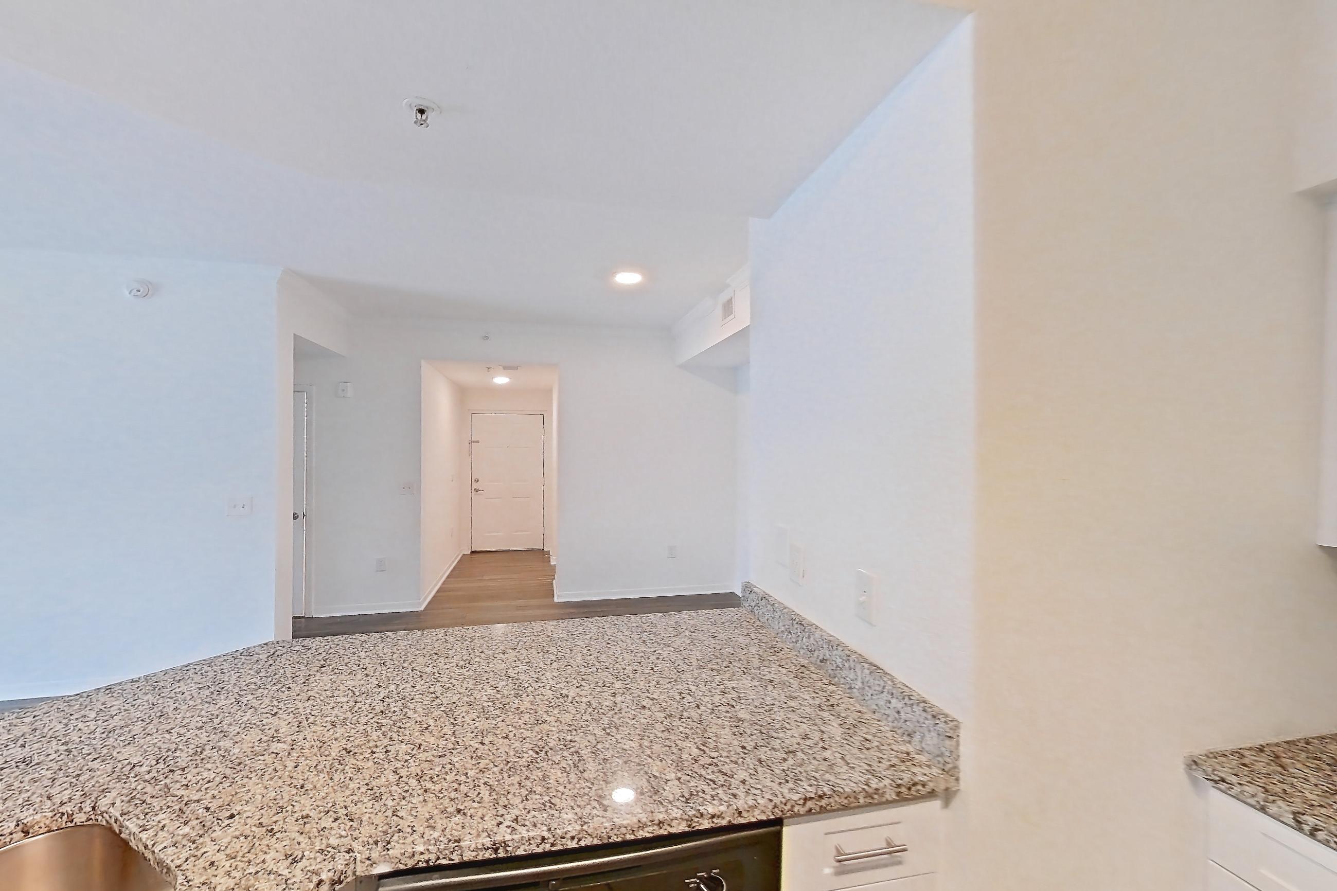 Kitchen with dark wood-finish flooring, dishwasher, electric range, light stone countertops, light wood-finish flooring, microwave, oven/range, refrigerator, and stainless steel appliances, Apartment 06-107 at Solano at Miramar