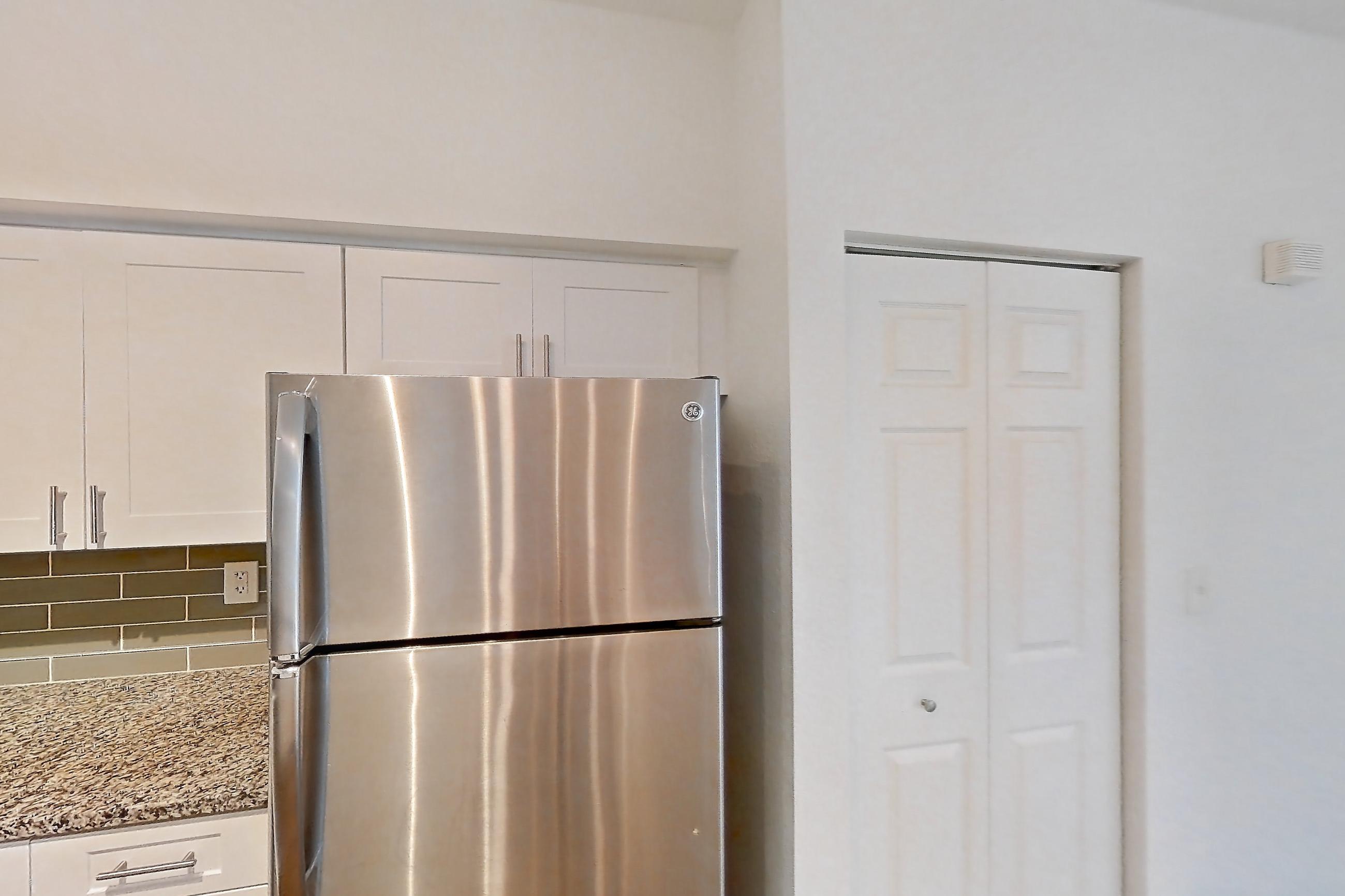 Kitchen with dark wood-finish flooring, dishwasher, electric range, light stone countertops, light wood-finish flooring, microwave, oven/range, refrigerator, and stainless steel appliances, Apartment 06-107 at Solano at Miramar
