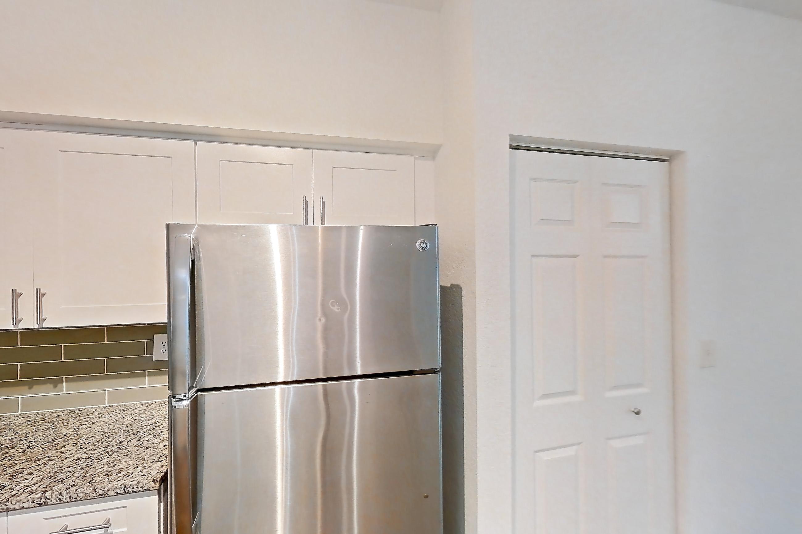 Kitchen with dark wood-finish flooring, dishwasher, electric range, light stone countertops, microwave, oven/range, refrigerator, and stainless steel appliances, Apartment 05-103 at Solano at Miramar