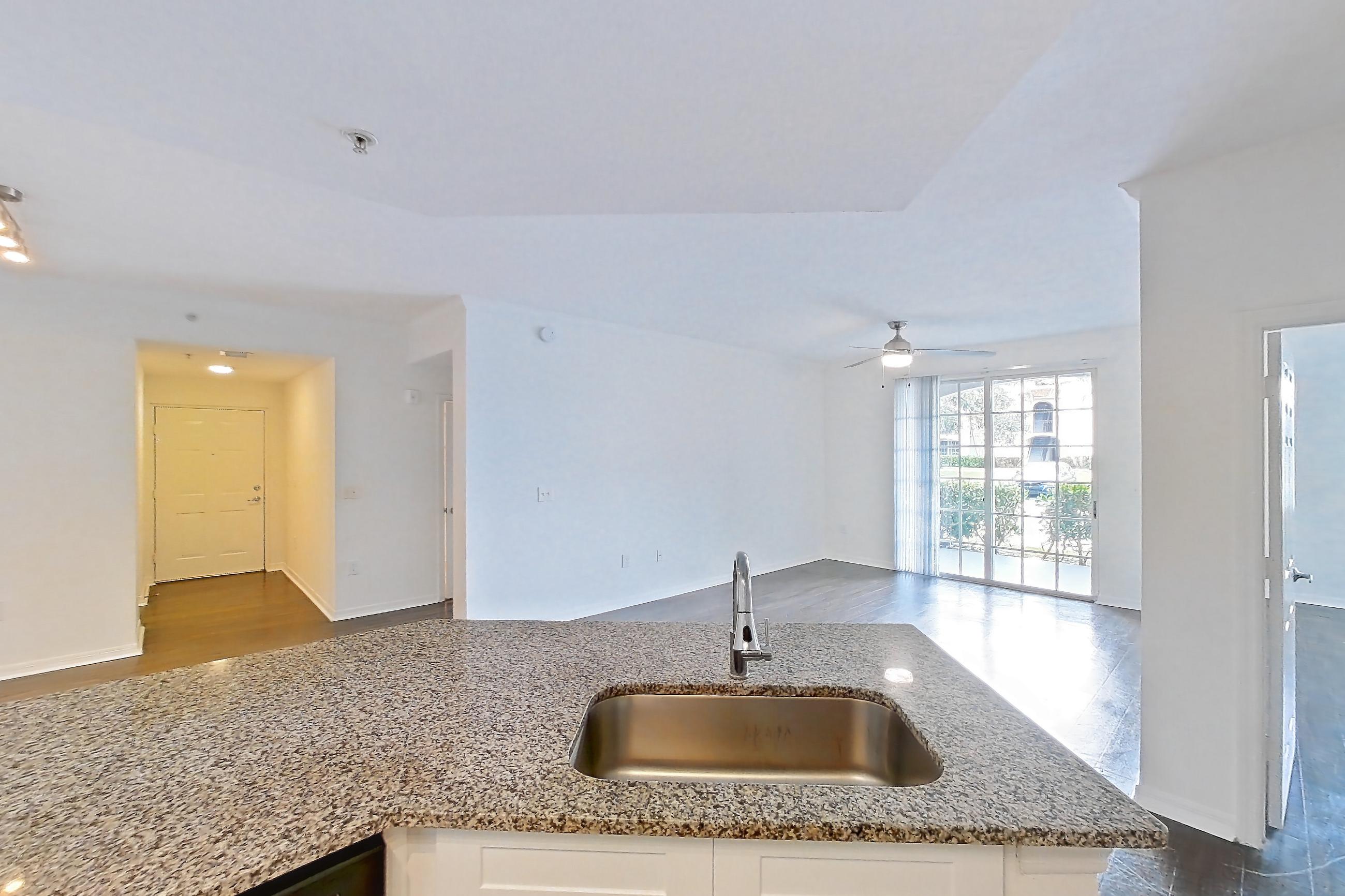 Kitchen with dark wood-finish flooring, dishwasher, electric range, light stone countertops, light wood-finish flooring, microwave, oven/range, refrigerator, and stainless steel appliances, Apartment 08-110 at Solano at Miramar